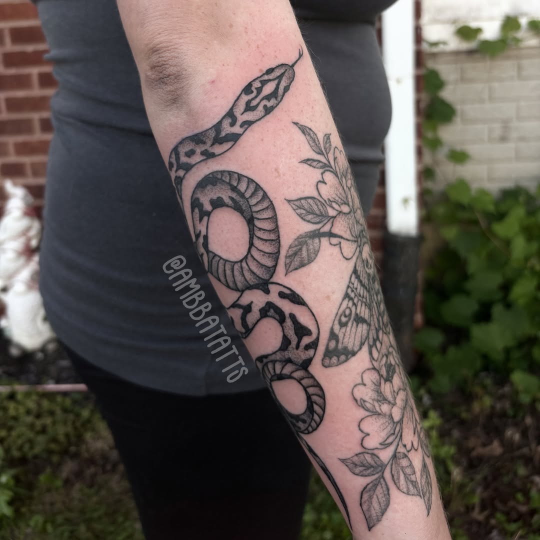 Snake and flowers black and grey tattoo on the forearm by amber brady, Brunswick, Ohio