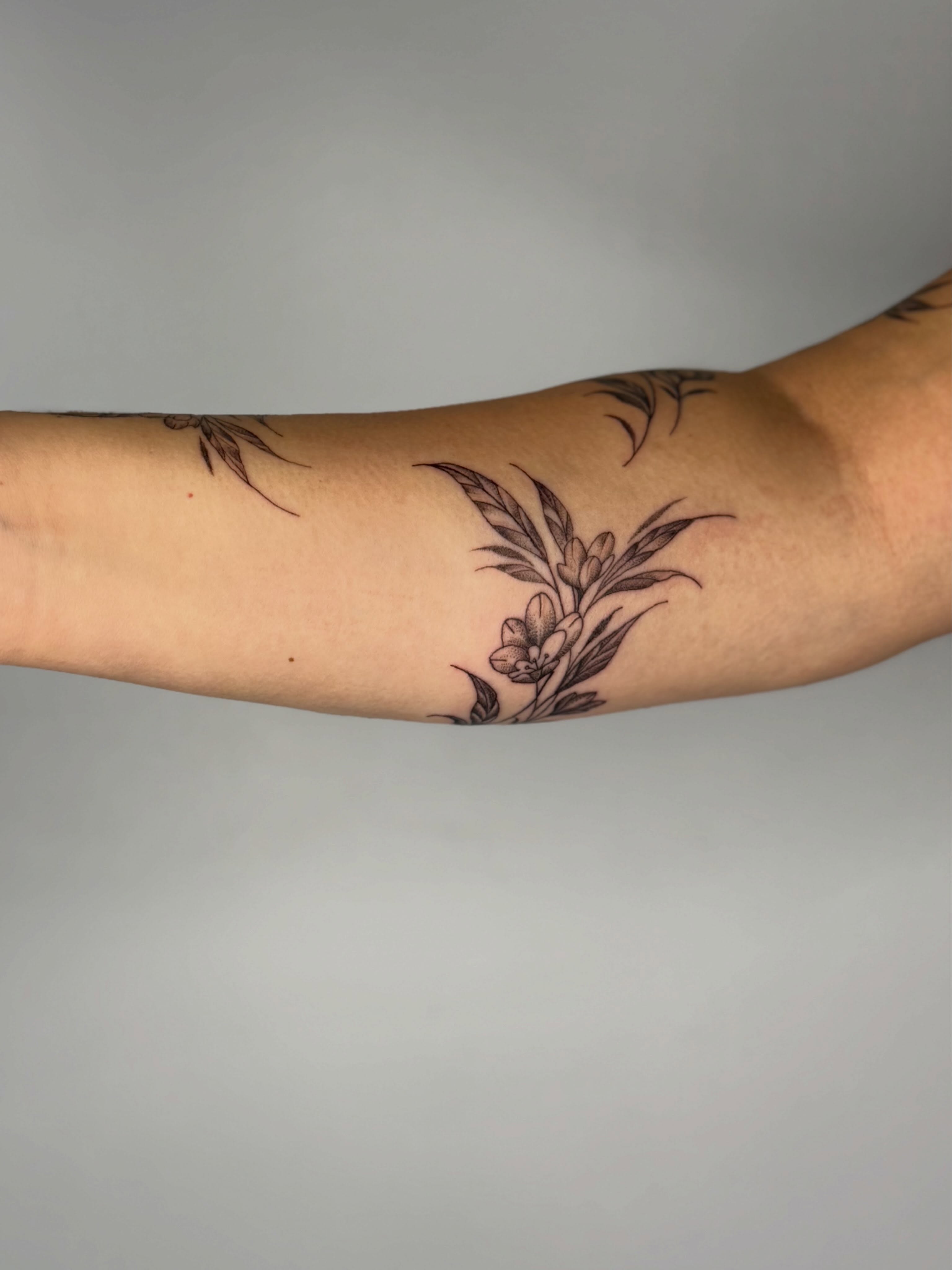 Floral arrangement black and grey tattoo on the forearm by Silva Wellen
