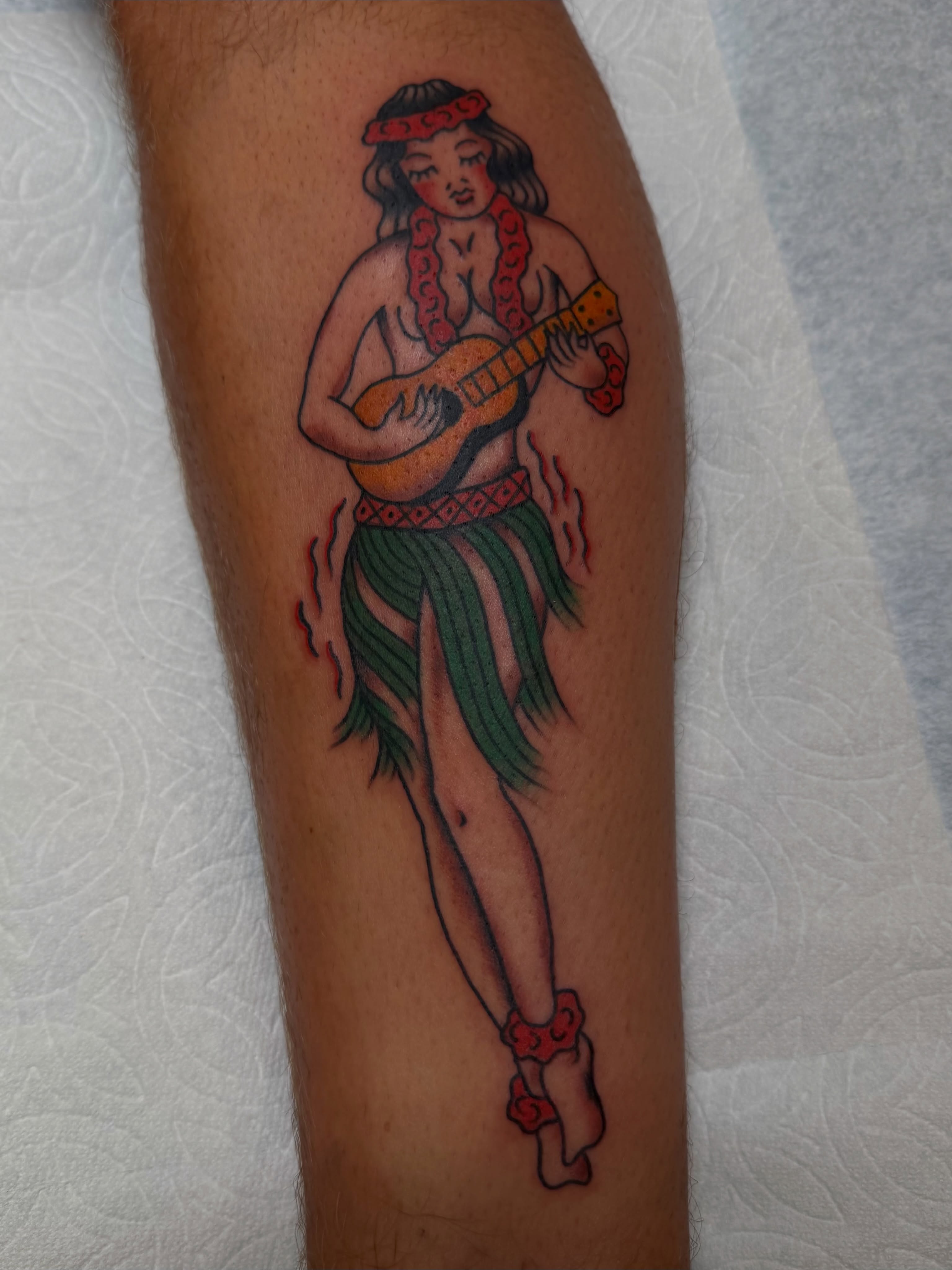 Hula dancer playing ukulele American traditional tattoo on the leg by Tyler Brown, San Diego, California
