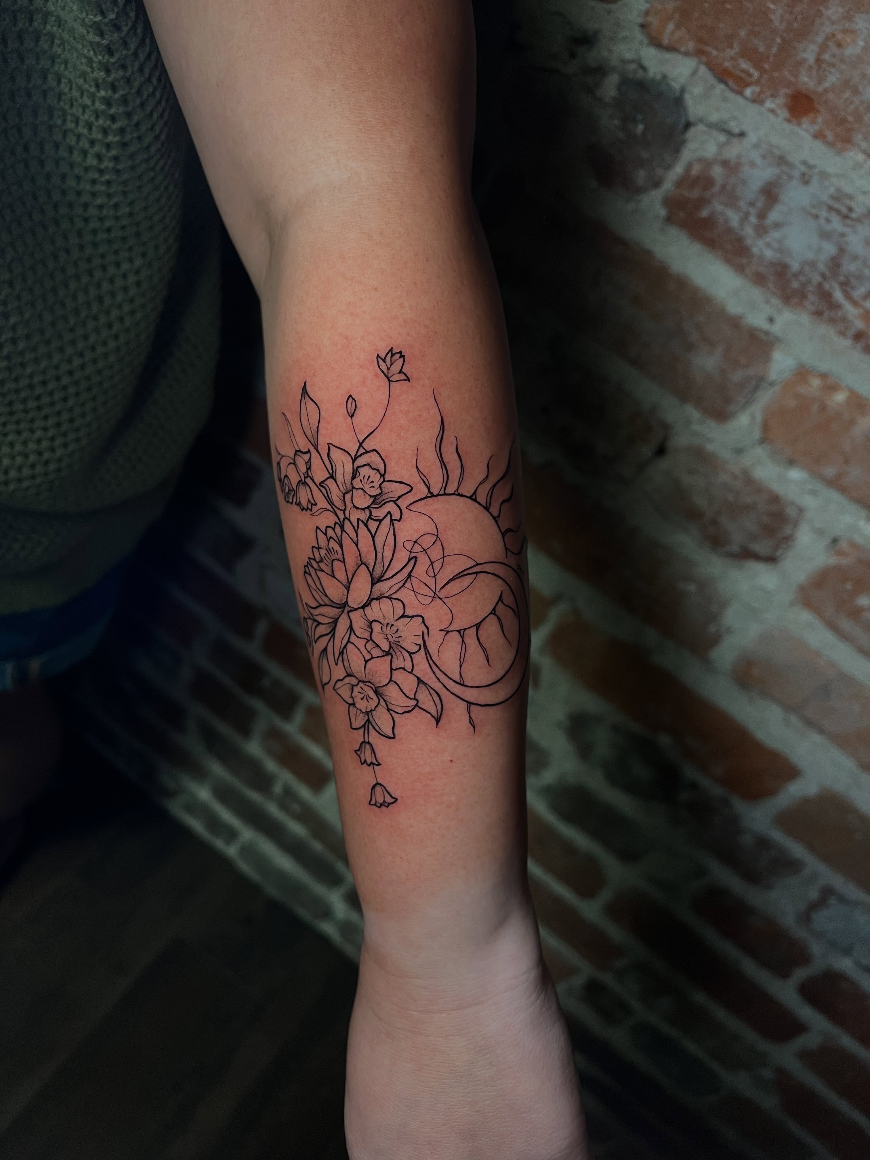 Floral arrangement black and grey tattoo on the forearm by Uncomfy Comfort Tattoos LLC
