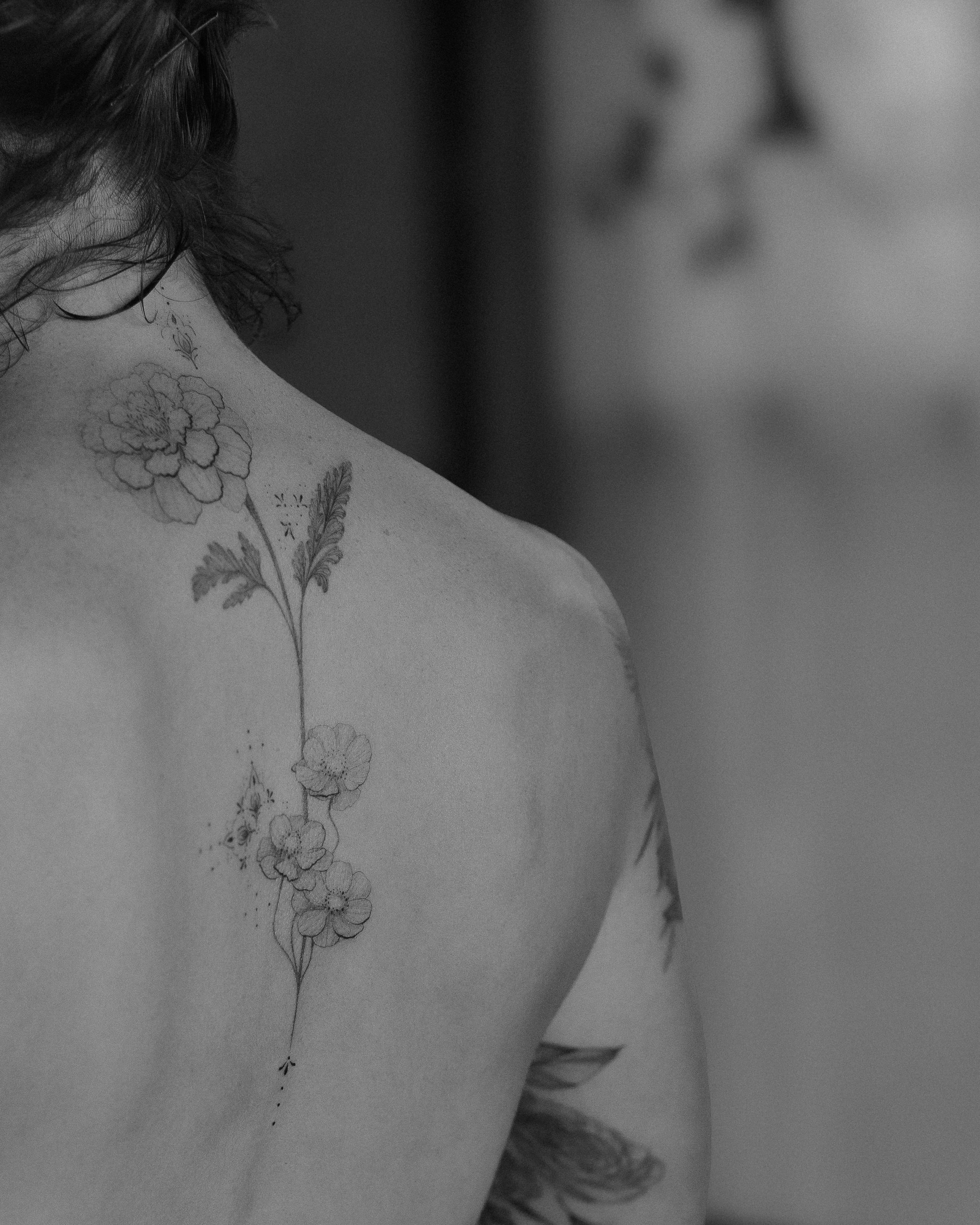 Flower arrangement black and grey tattoo on the back by Aries Rising