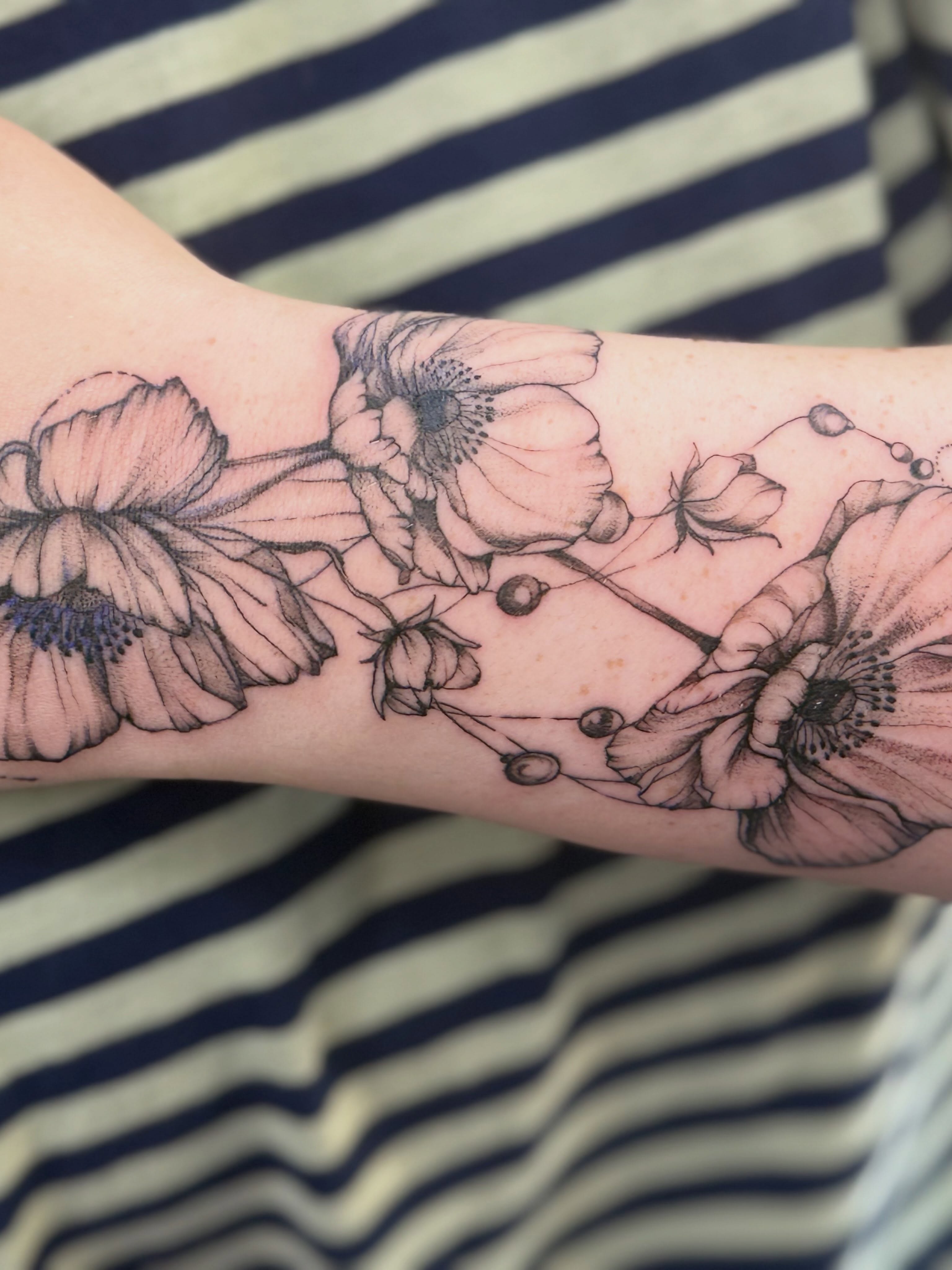 Flowers black and grey tattoo on the forearm by Tetiana