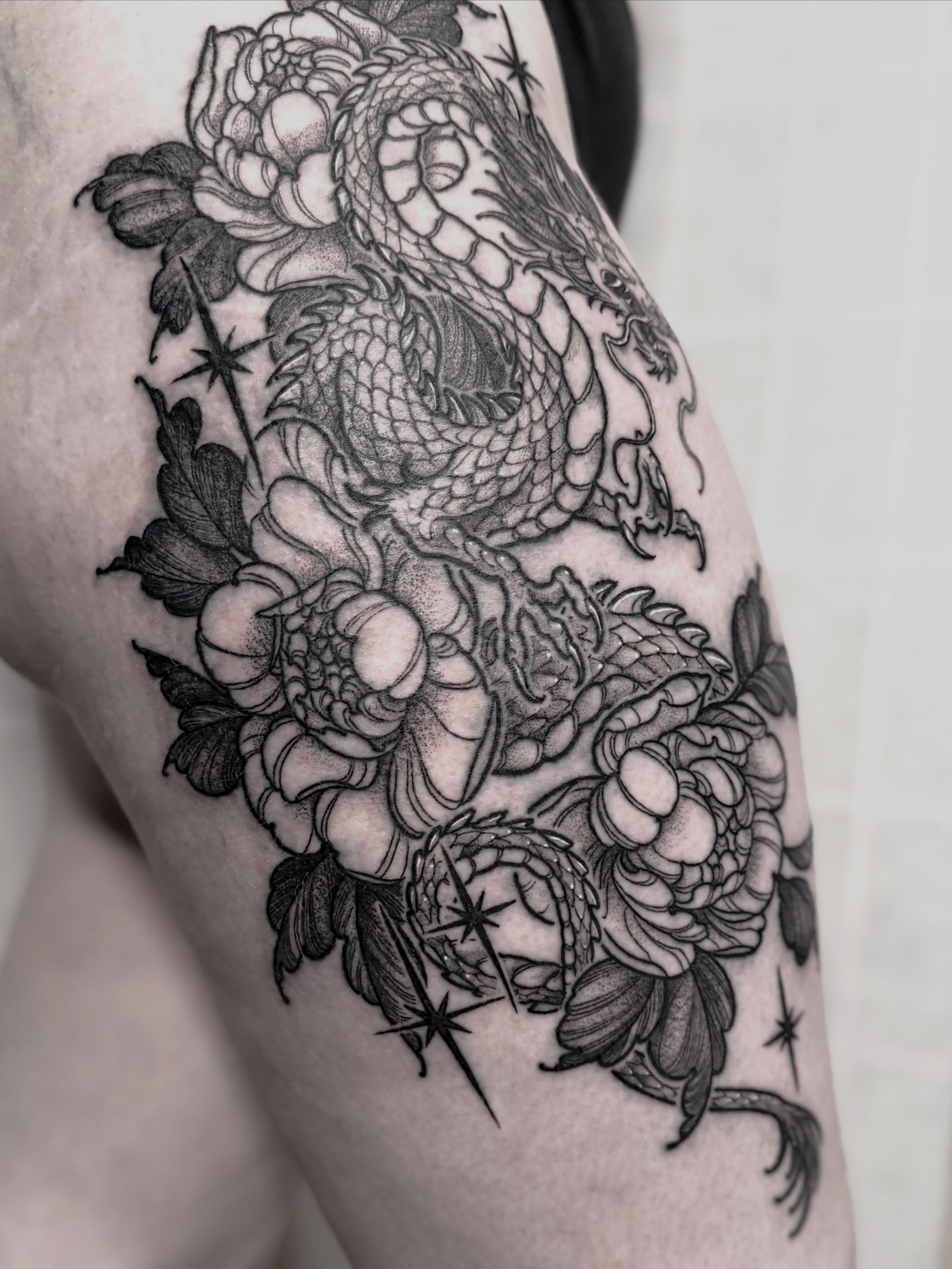 Dragon and flowers realism tattoo on the thigh by Cincinnati