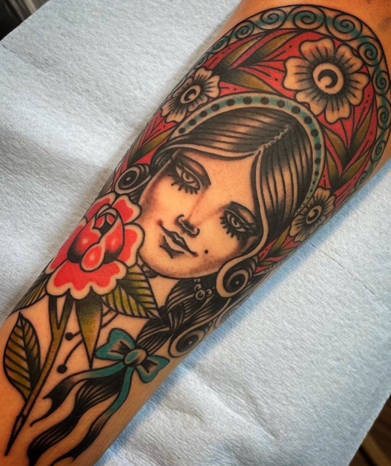 Woman with floral crown American traditional tattoo on the forearm by Rogelio Robles