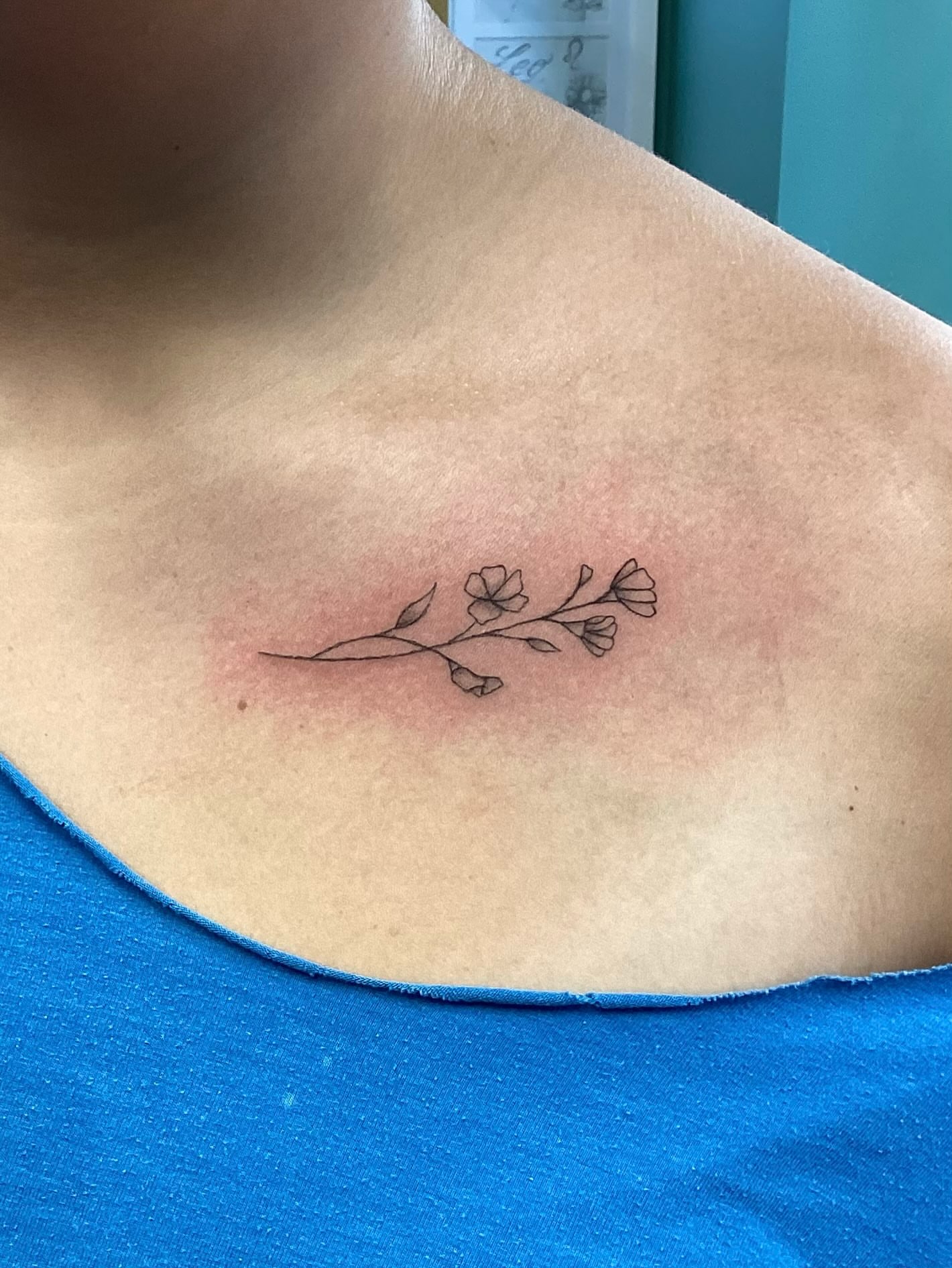 Flower branch fine line tattoo on the chest by Amanda Plavan