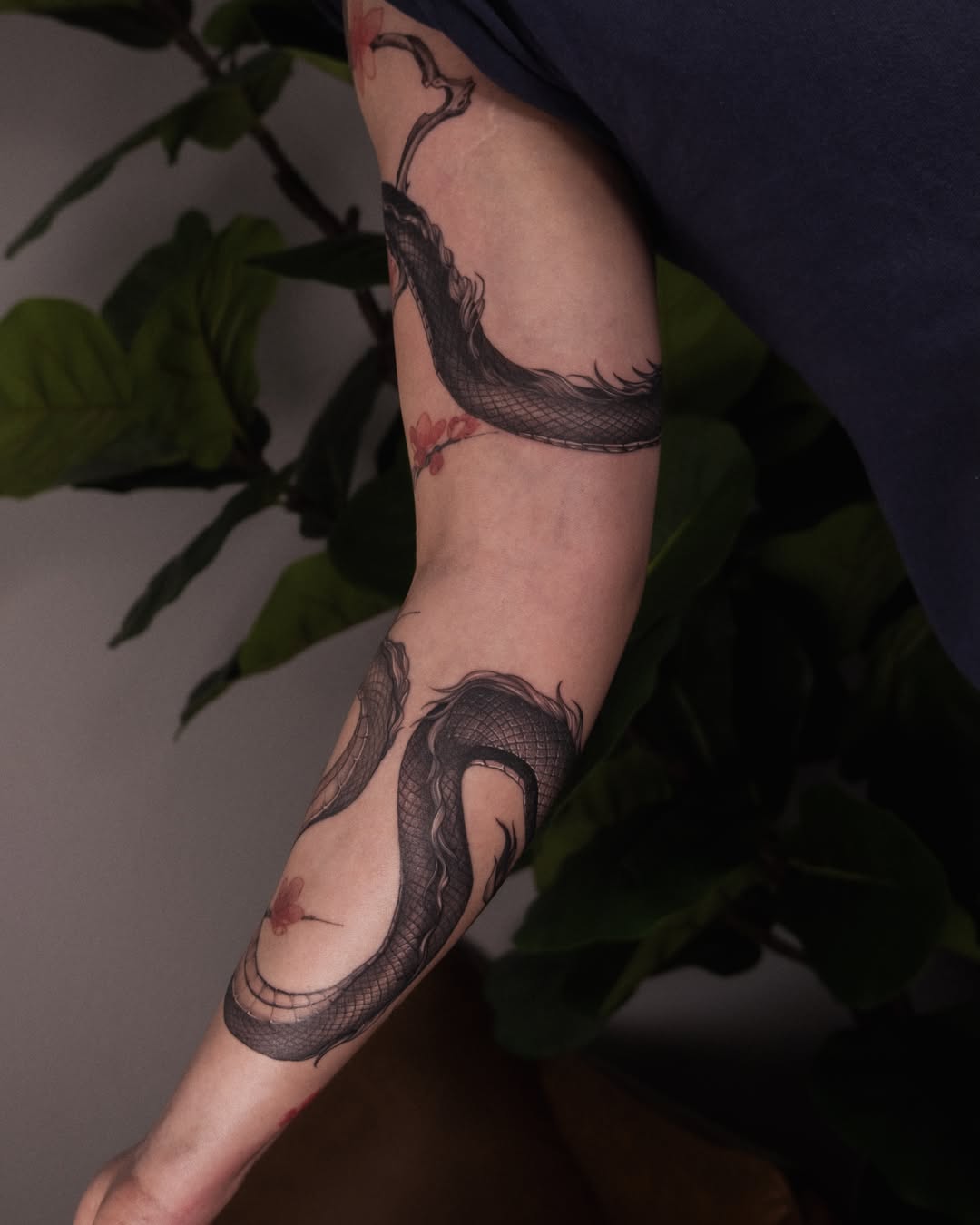 Snake and peony black and grey tattoo on the forearm by Wong Lee