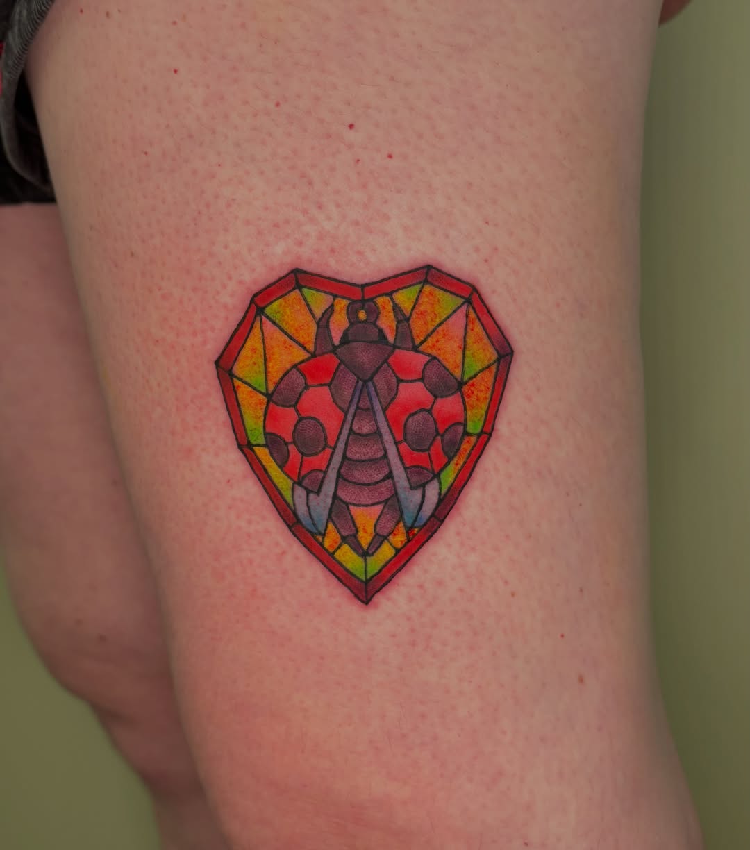 Stained glass heart with insect geometric tattoo on the thigh by Chloe Shay