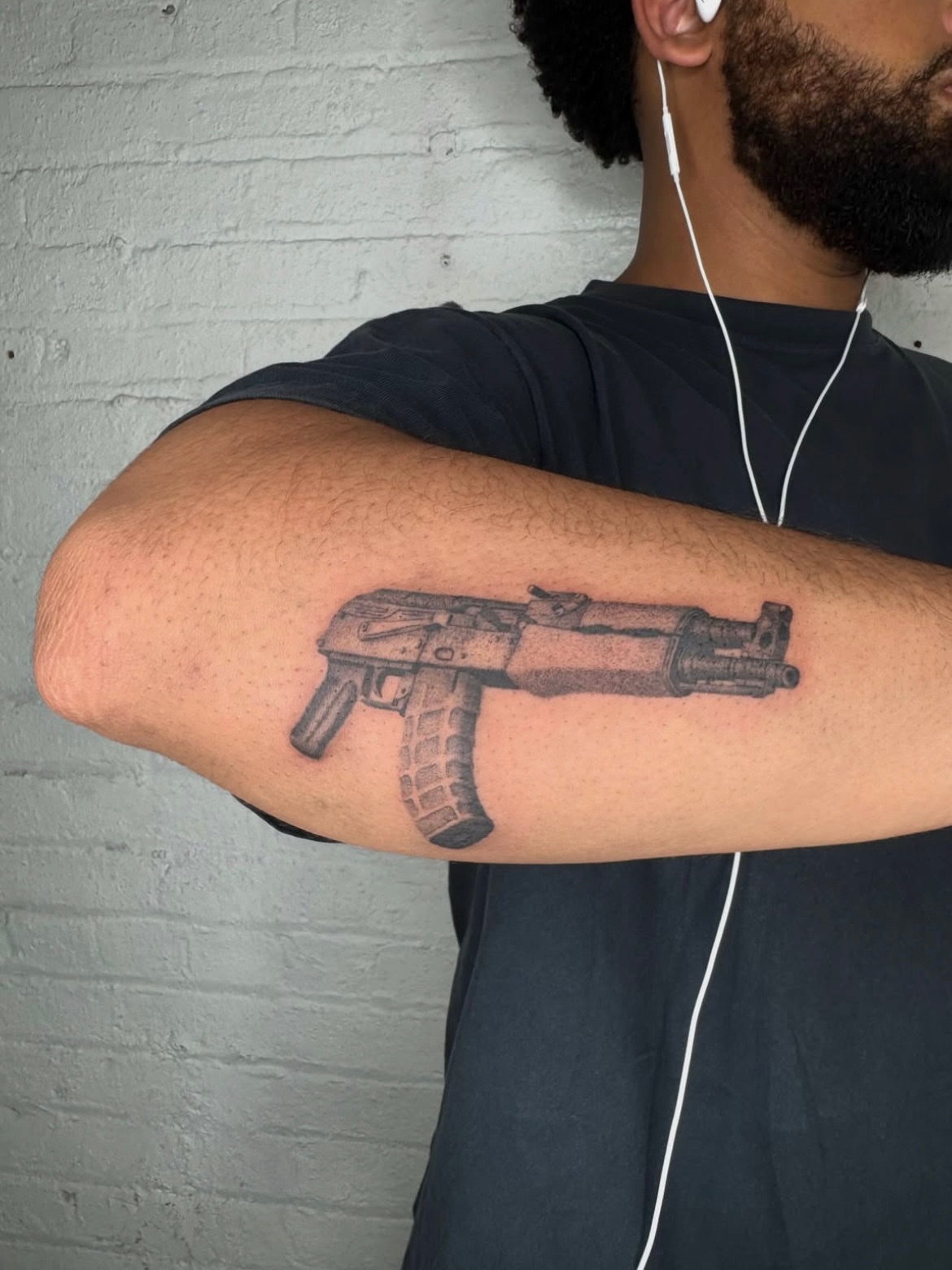Machine gun black and grey tattoo on the forearm by Kenny ๐ด