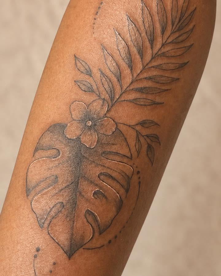 Monstera leaf and flowers black and grey tattoo on the forearm by Flamboyant
