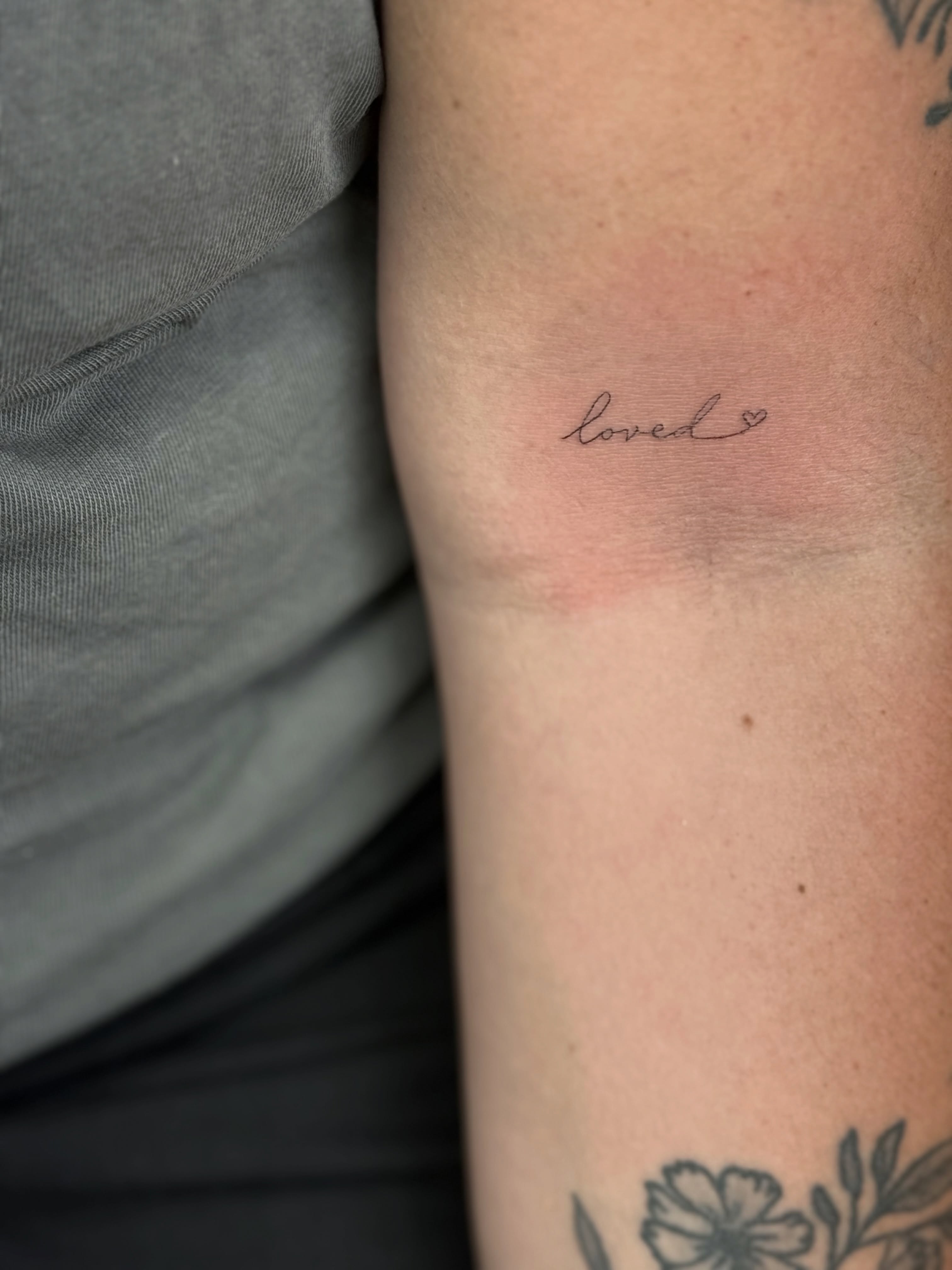 Loved lettering script tattoo on the forearm by Fineline Tattoo
