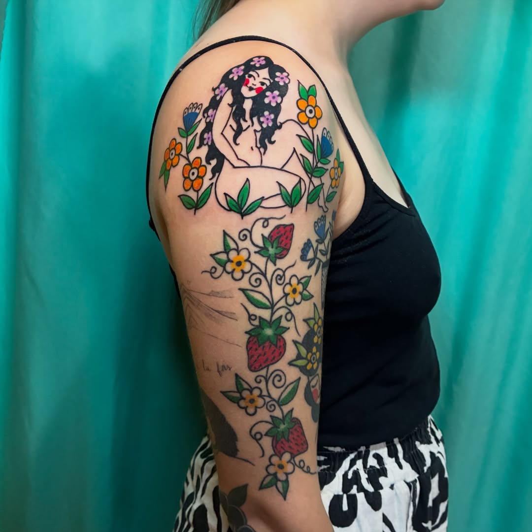 Female figure with flowers American traditional tattoo on the upper arm by Kaily McKee
