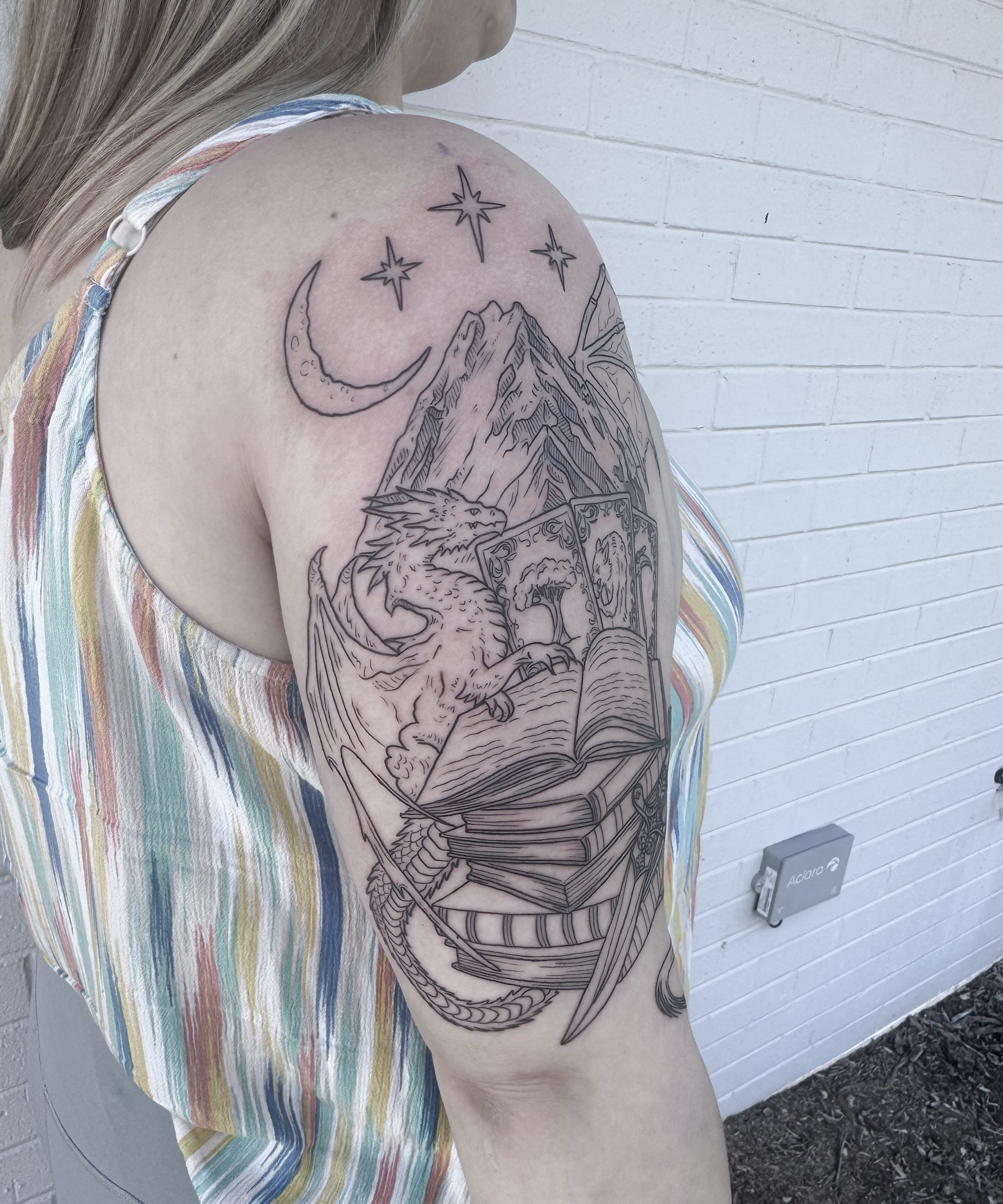 Book with eagle and mountain realism tattoo on the shoulder by Audrey Kacel, Holland, Michigan