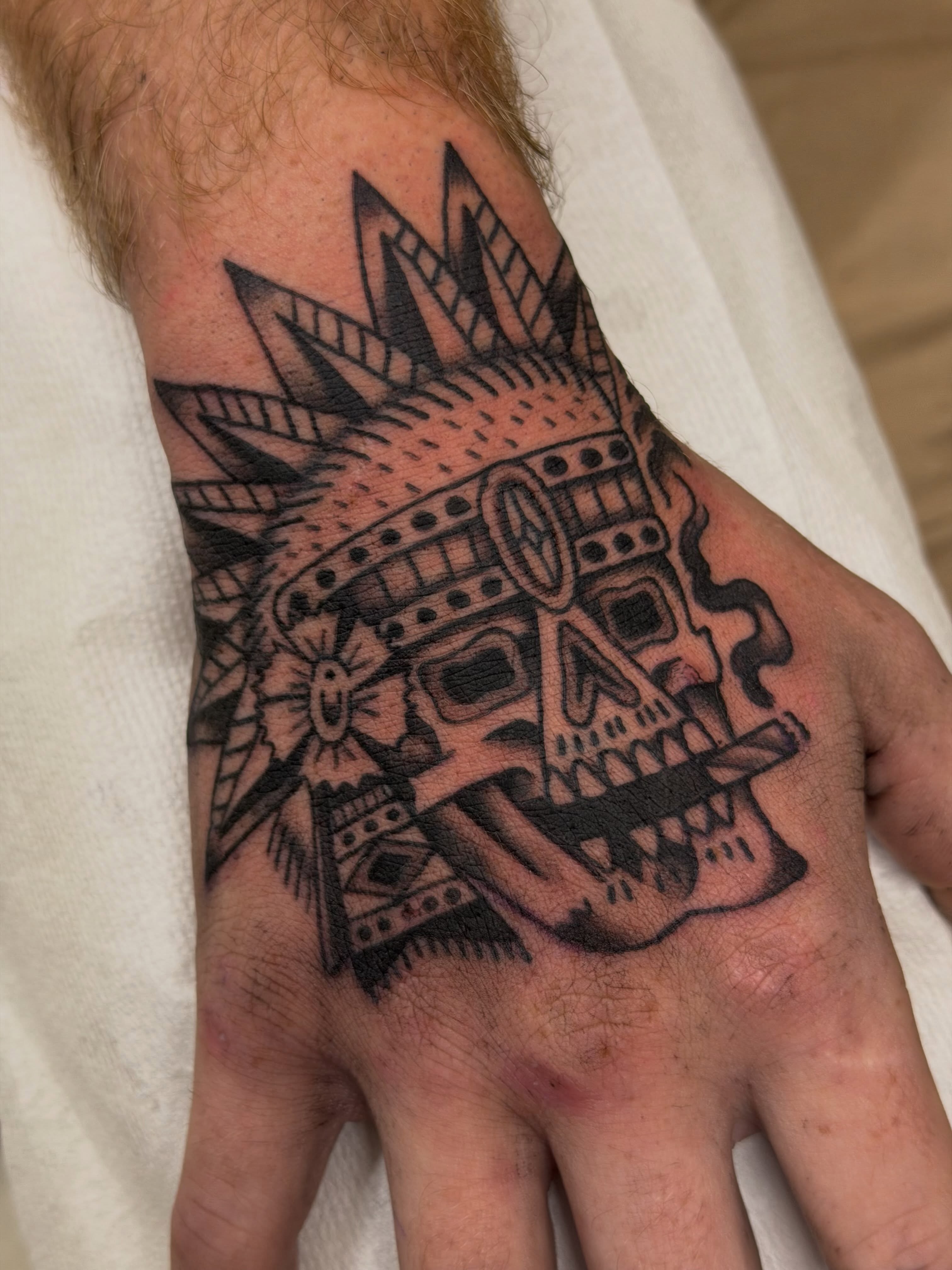 Skull mask black and grey tattoo on the hand by Gerald Bellmore
