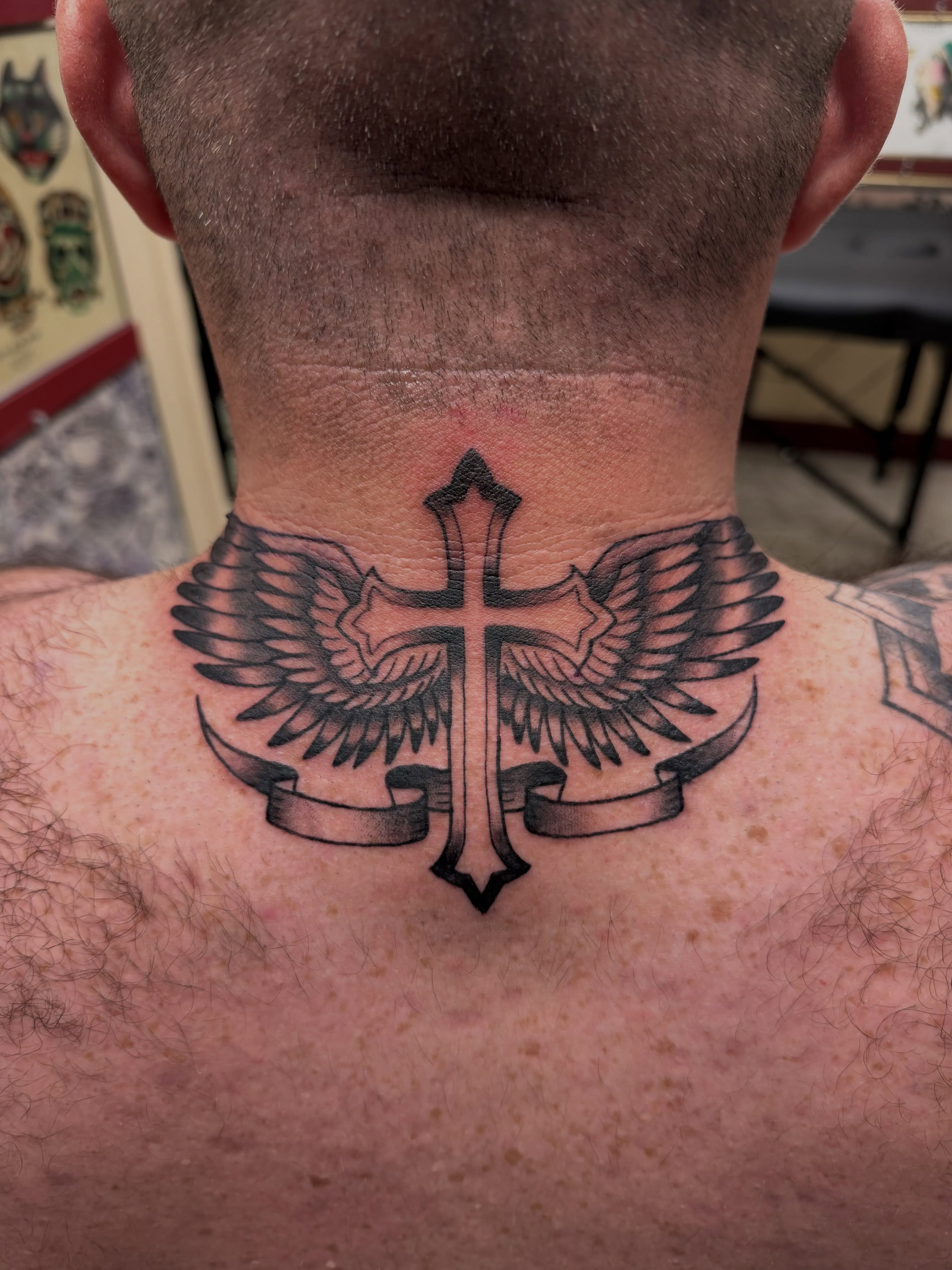 Cross with wings black and grey tattoo on the neck by Gerald Bellmore