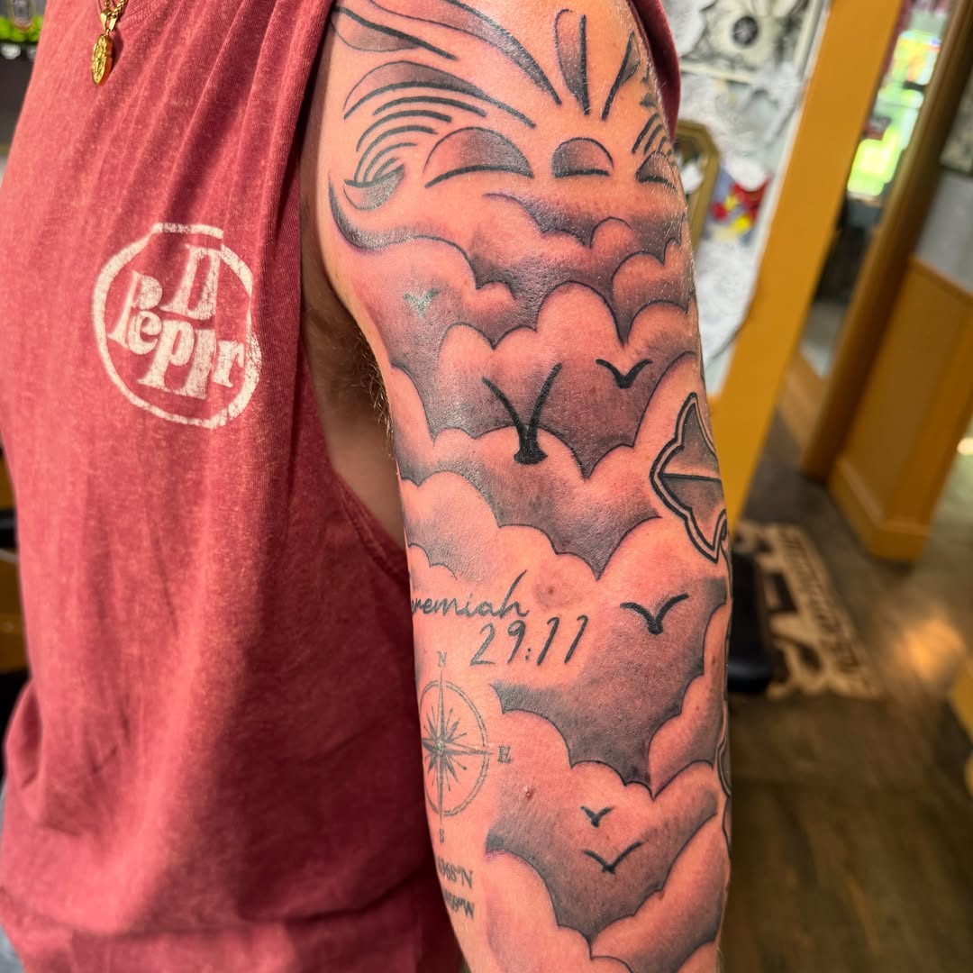 Clouds and birds black and grey tattoo on the forearm by Will Eagle
