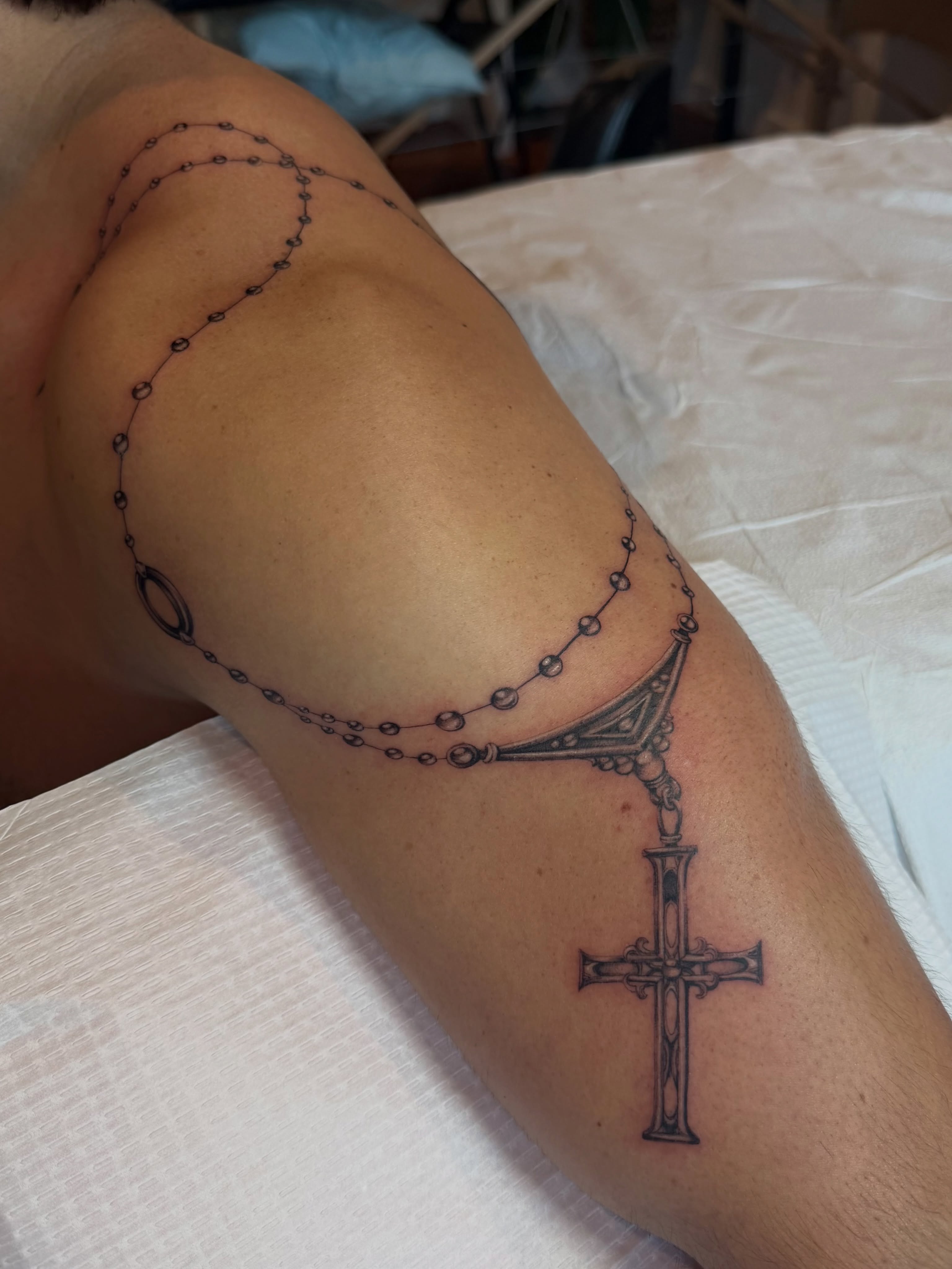 Rosary and cross black and grey tattoo on the forearm by Lauren ๐