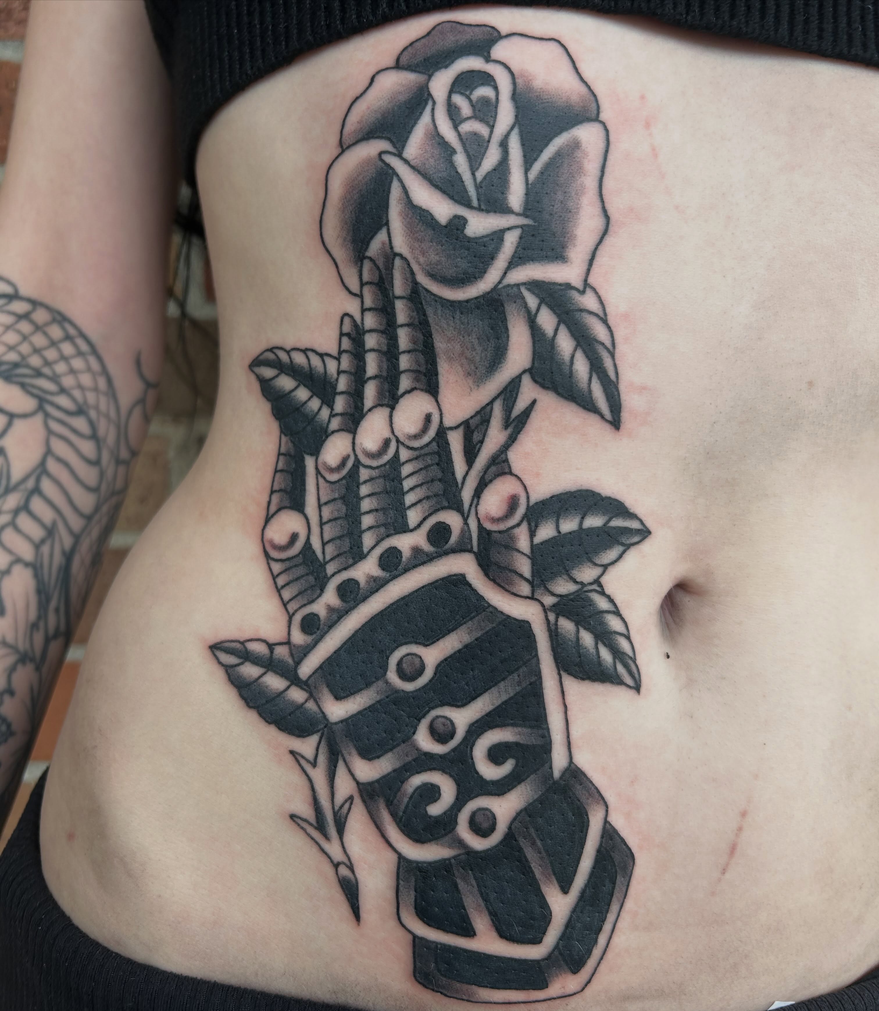 Rose and skeleton hand American traditional tattoo on the ribs by Donny