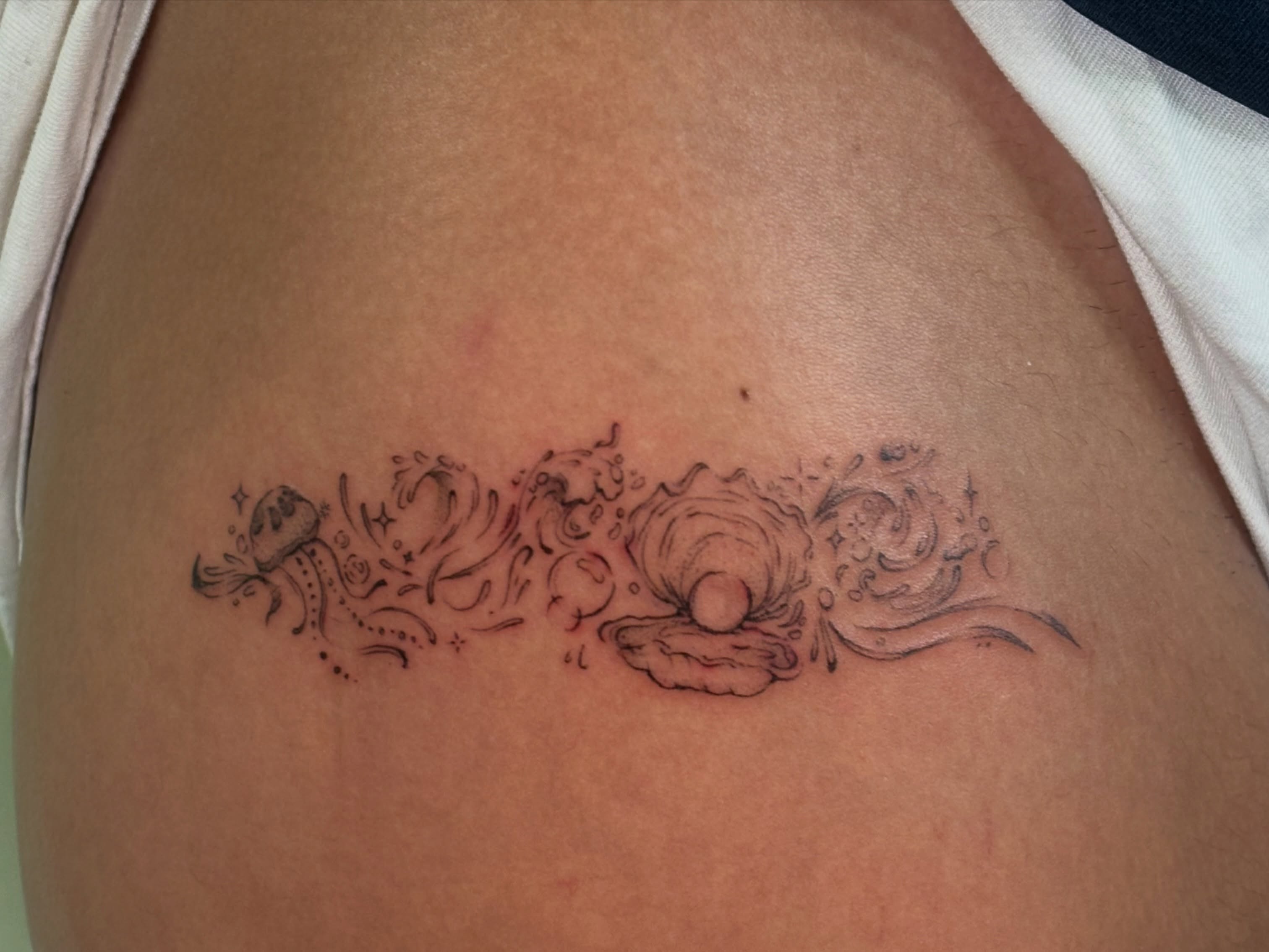 Shell and hands black and grey tattoo on the ribs by Chloe Shay