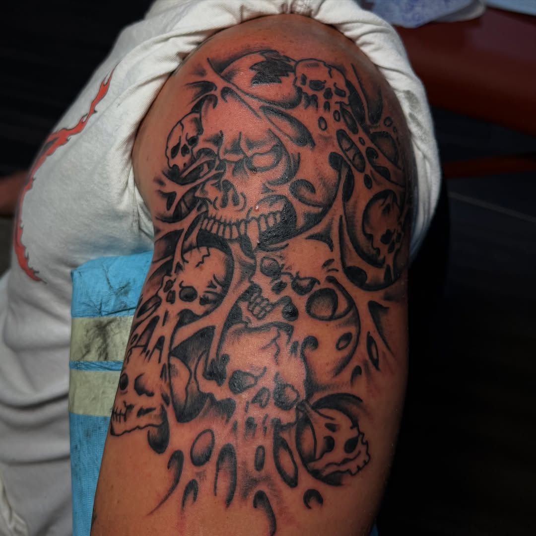 Skulls black and grey tattoo on the upper arm by c☮︎urt