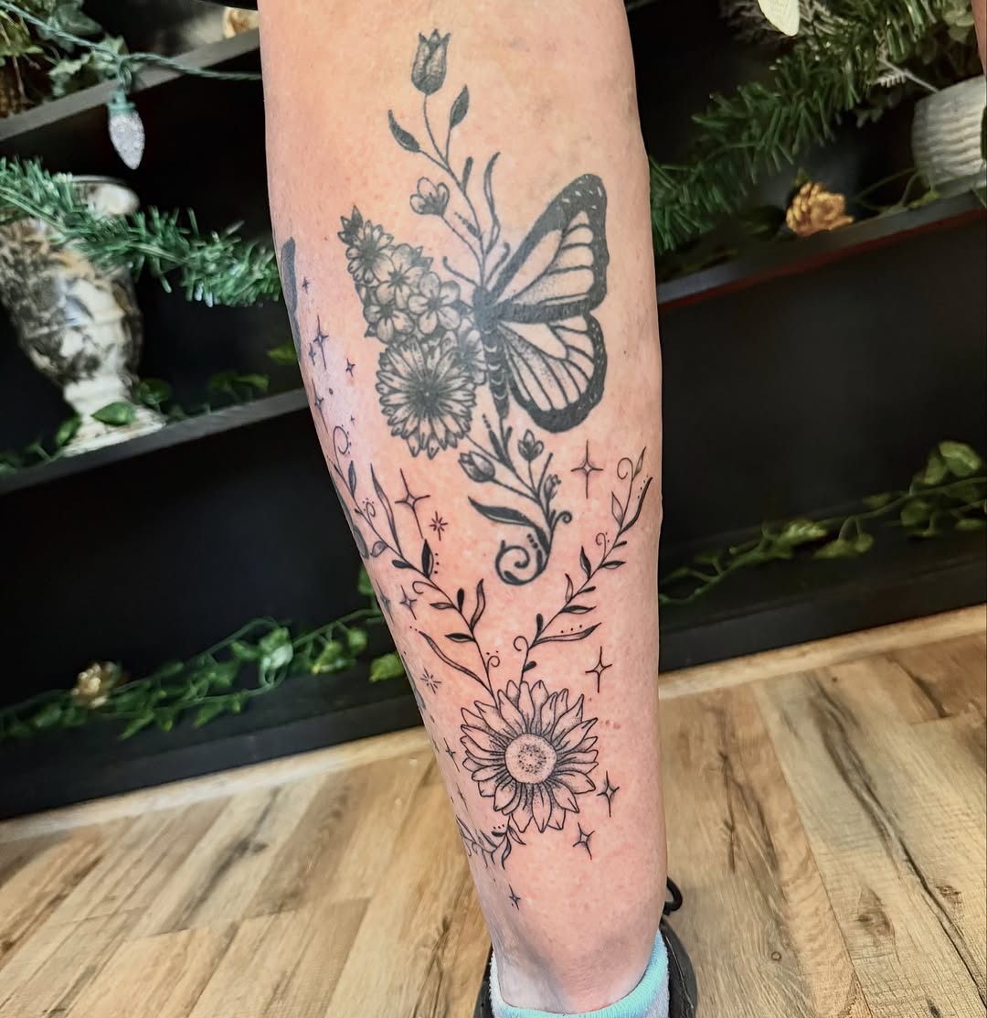 Butterfly and flowers black and grey tattoo on the forearm by Haley Bates