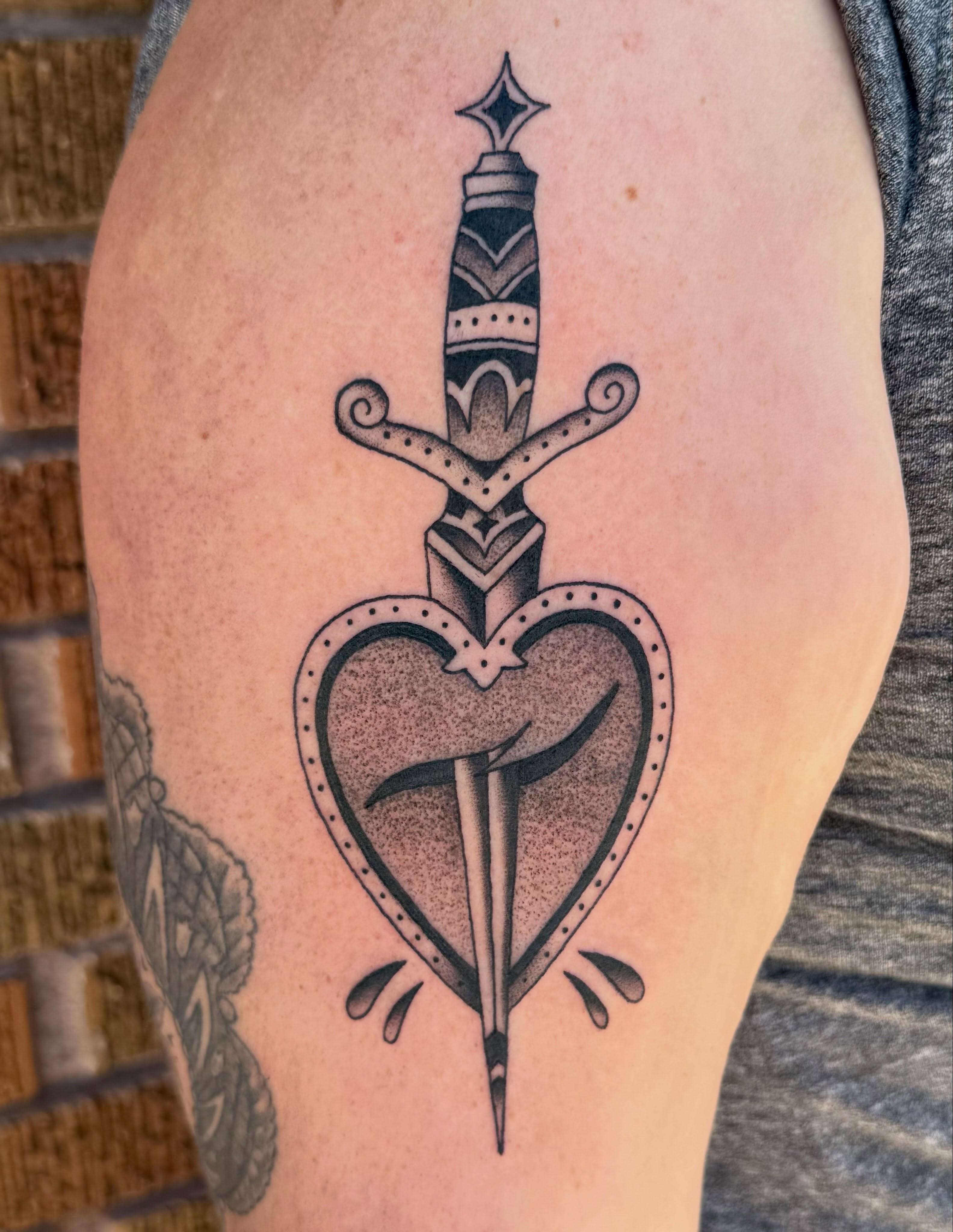 Heart with dagger American traditional tattoo on the thigh by Sophie McTear