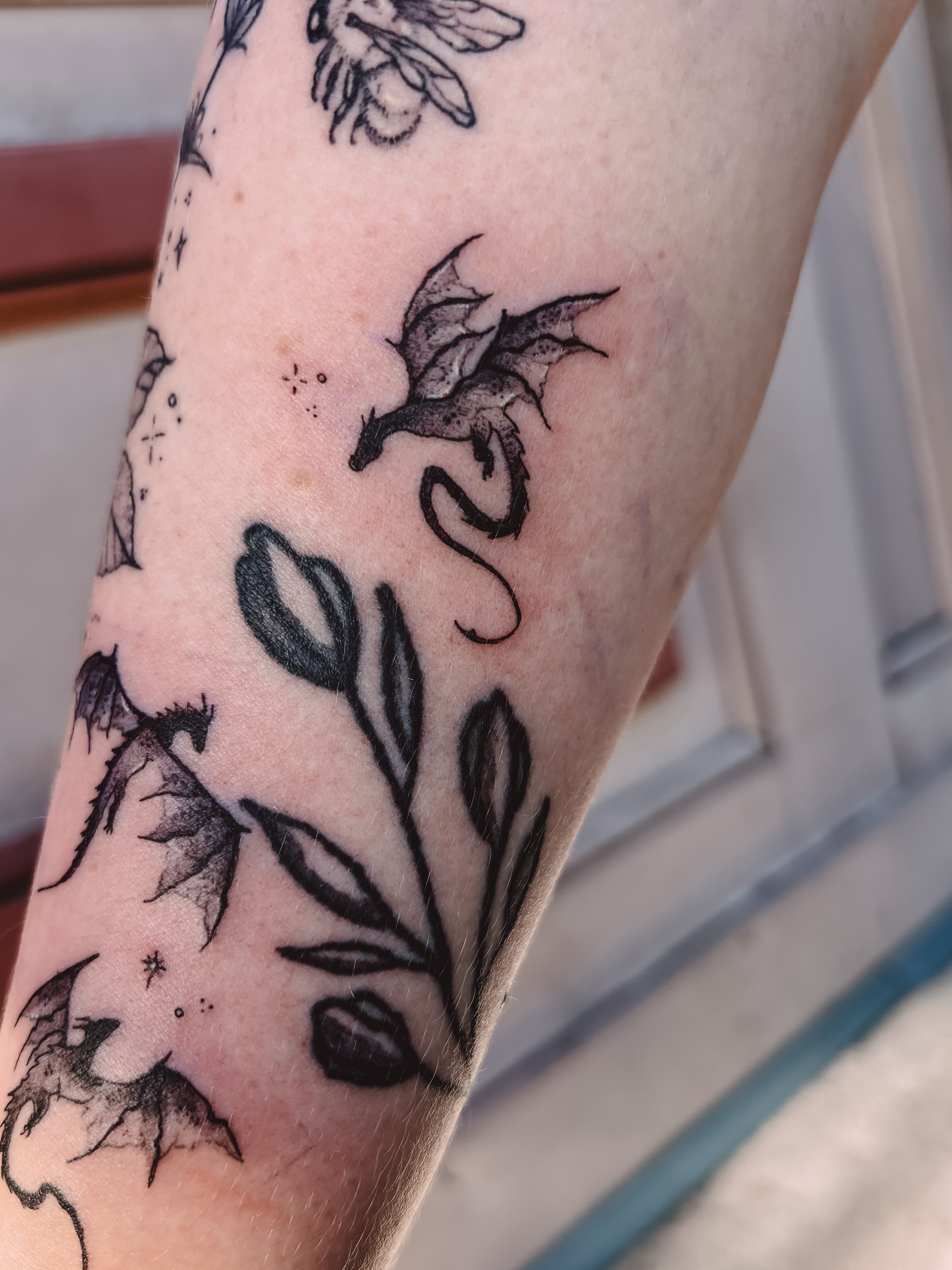 Dragon and tulips black and grey tattoo on the forearm by Liz Cook