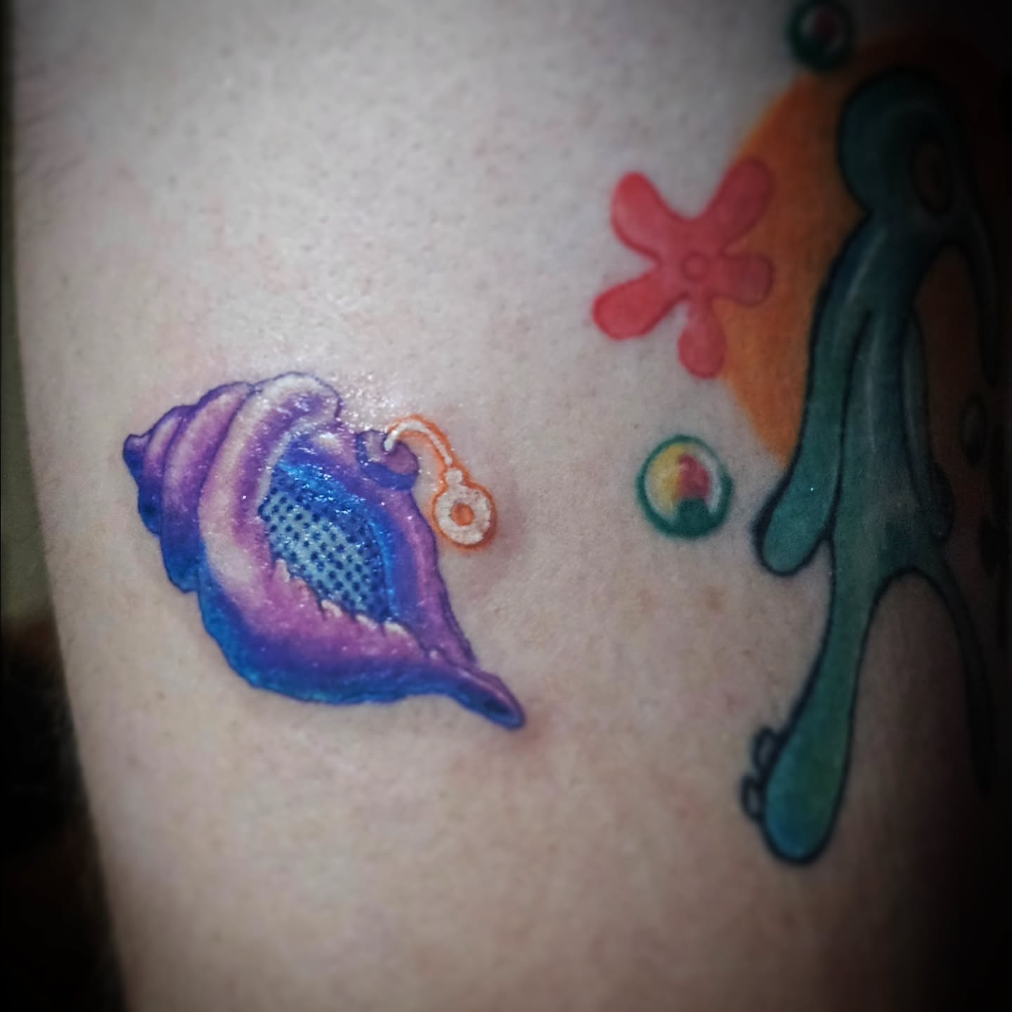 Seashell and fish new school tattoo on the upper arm by Ari 💠🧜‍♂️🐟🎨🦑🐚💠