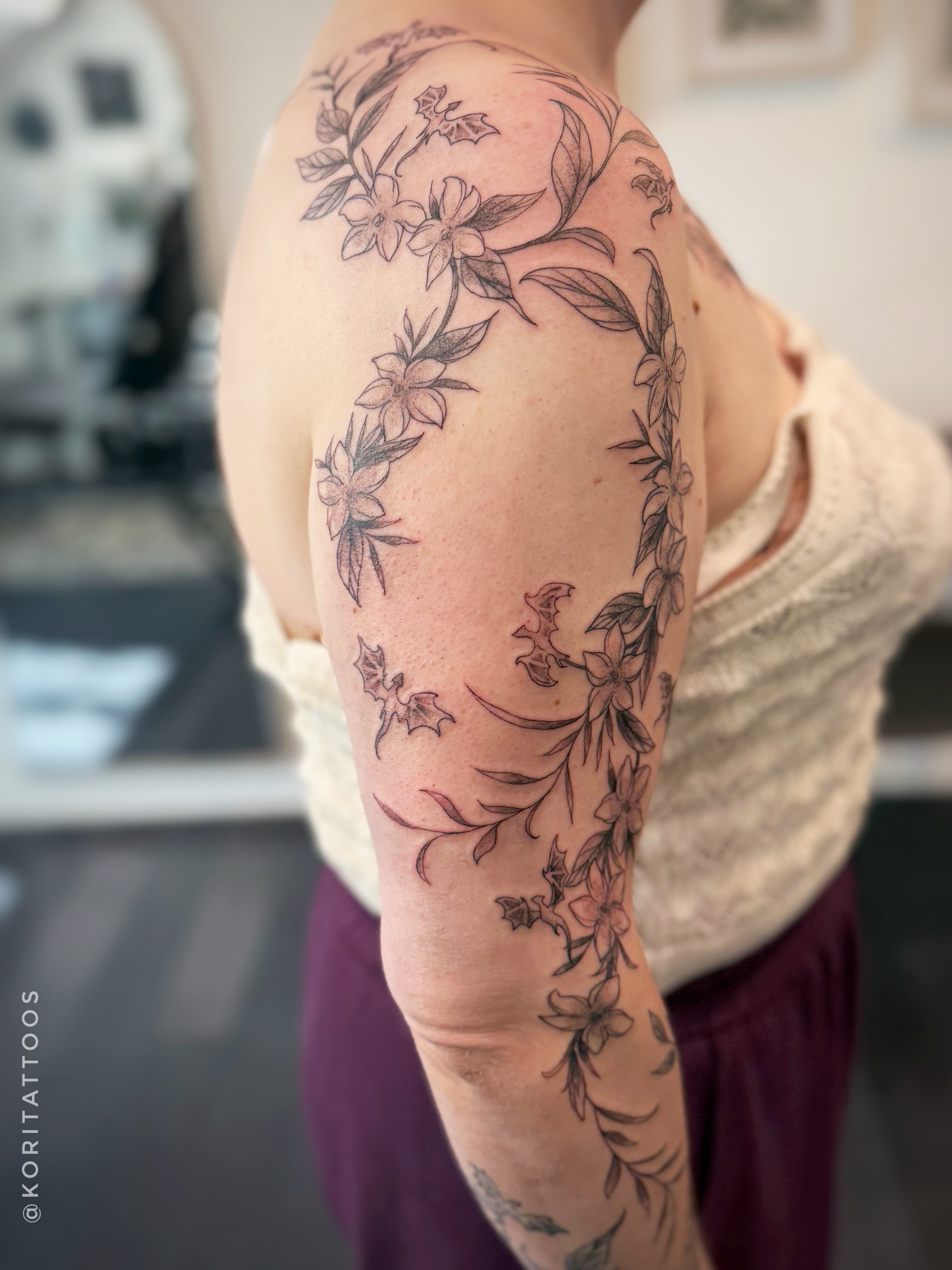 Floral vine black and grey tattoo on the upper arm by Kori Millhimes