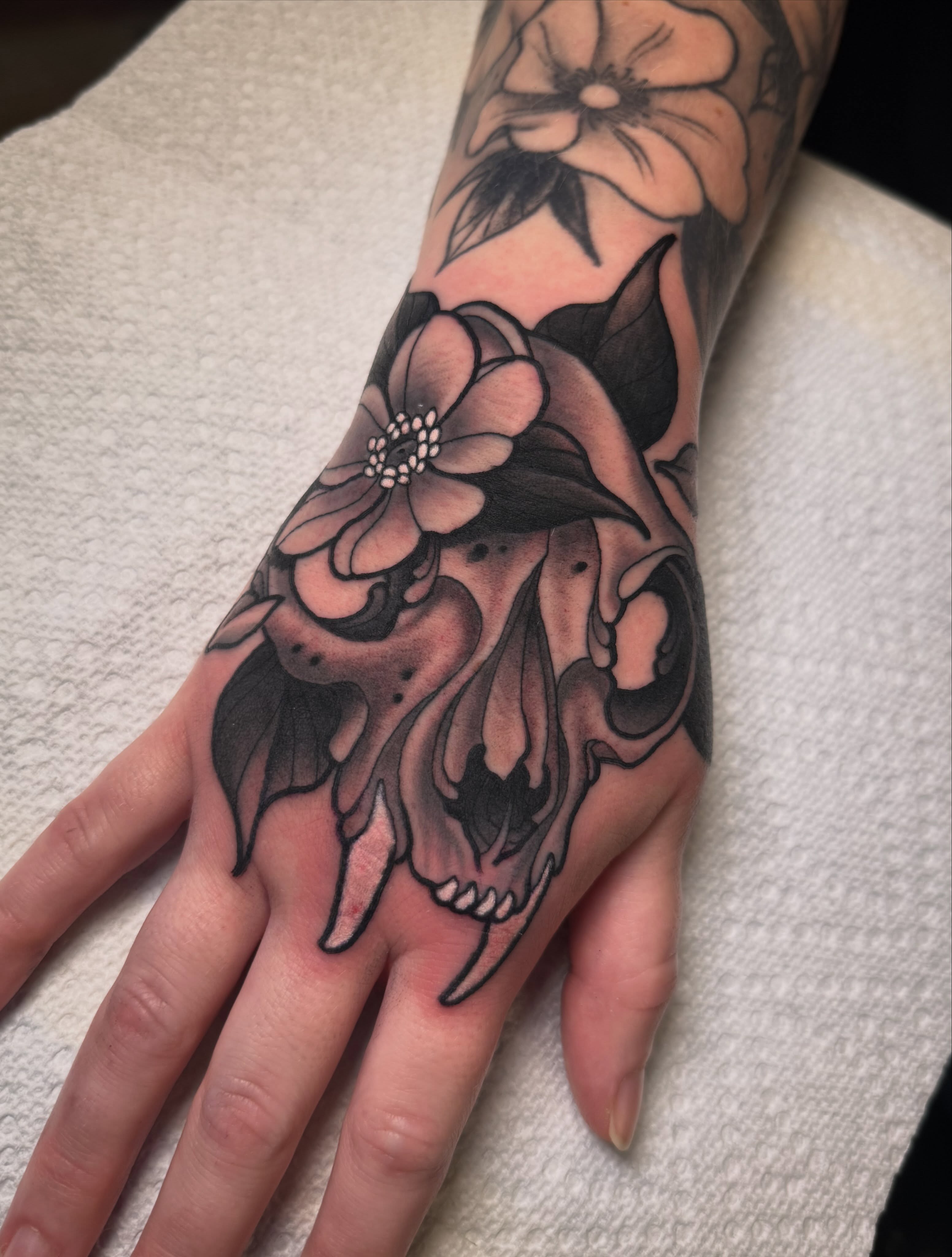 Skull and flowers American traditional tattoo on the hand by Jess Longfield, Des Moines, Iowa