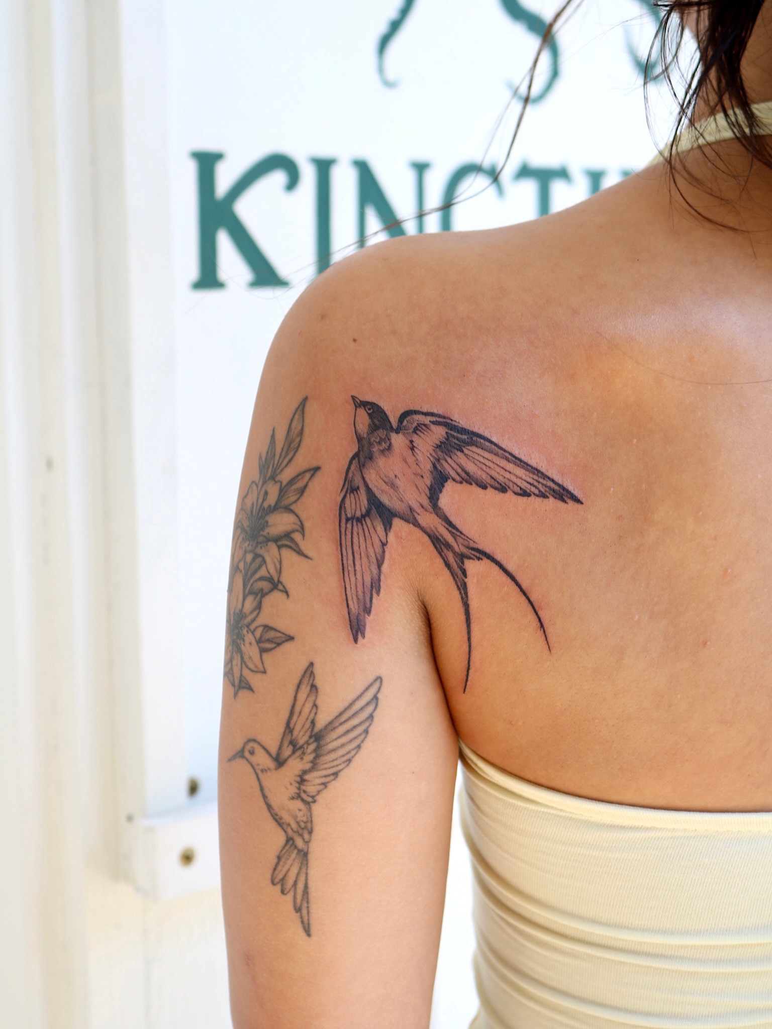 Swallow and flowers realism tattoo on the shoulder by Kingtide Ink