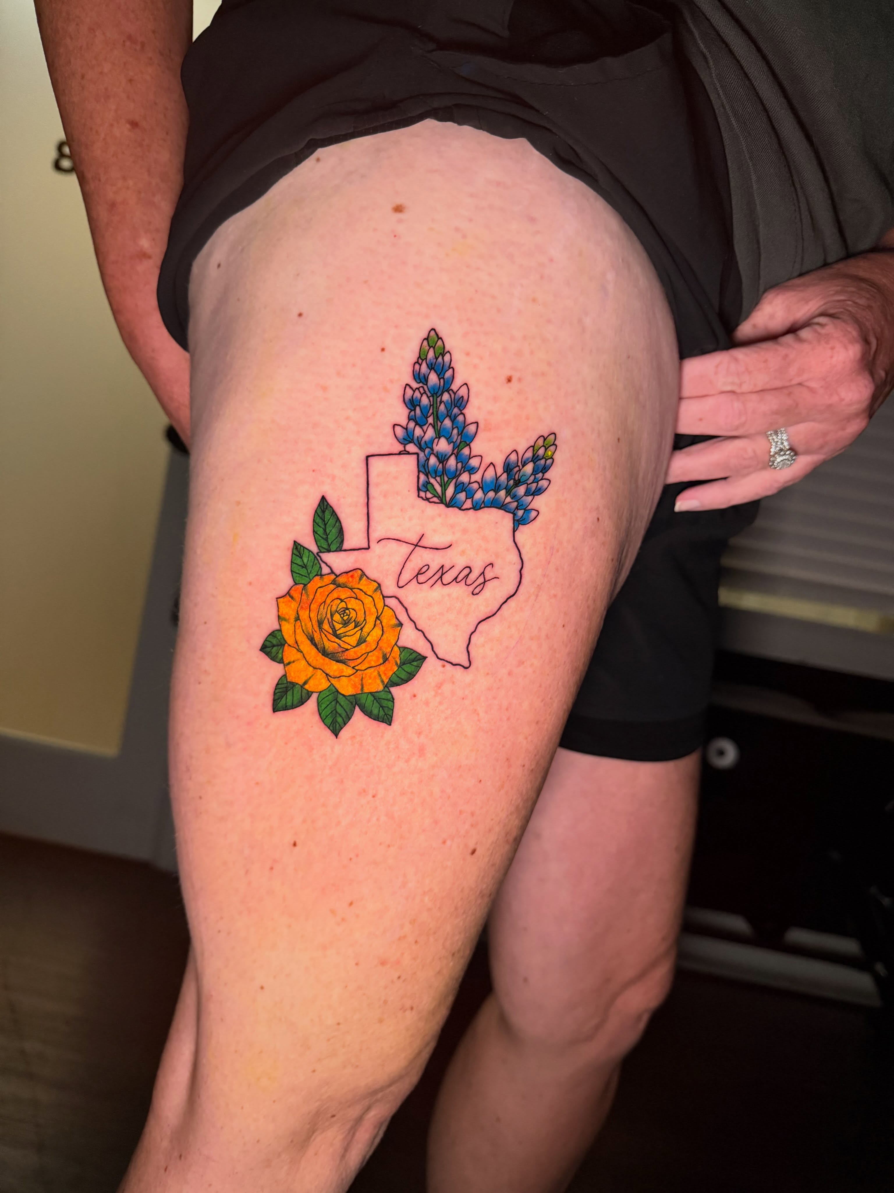 Texas state outline with flowers American traditional tattoo on the thigh by Delaney Cooper