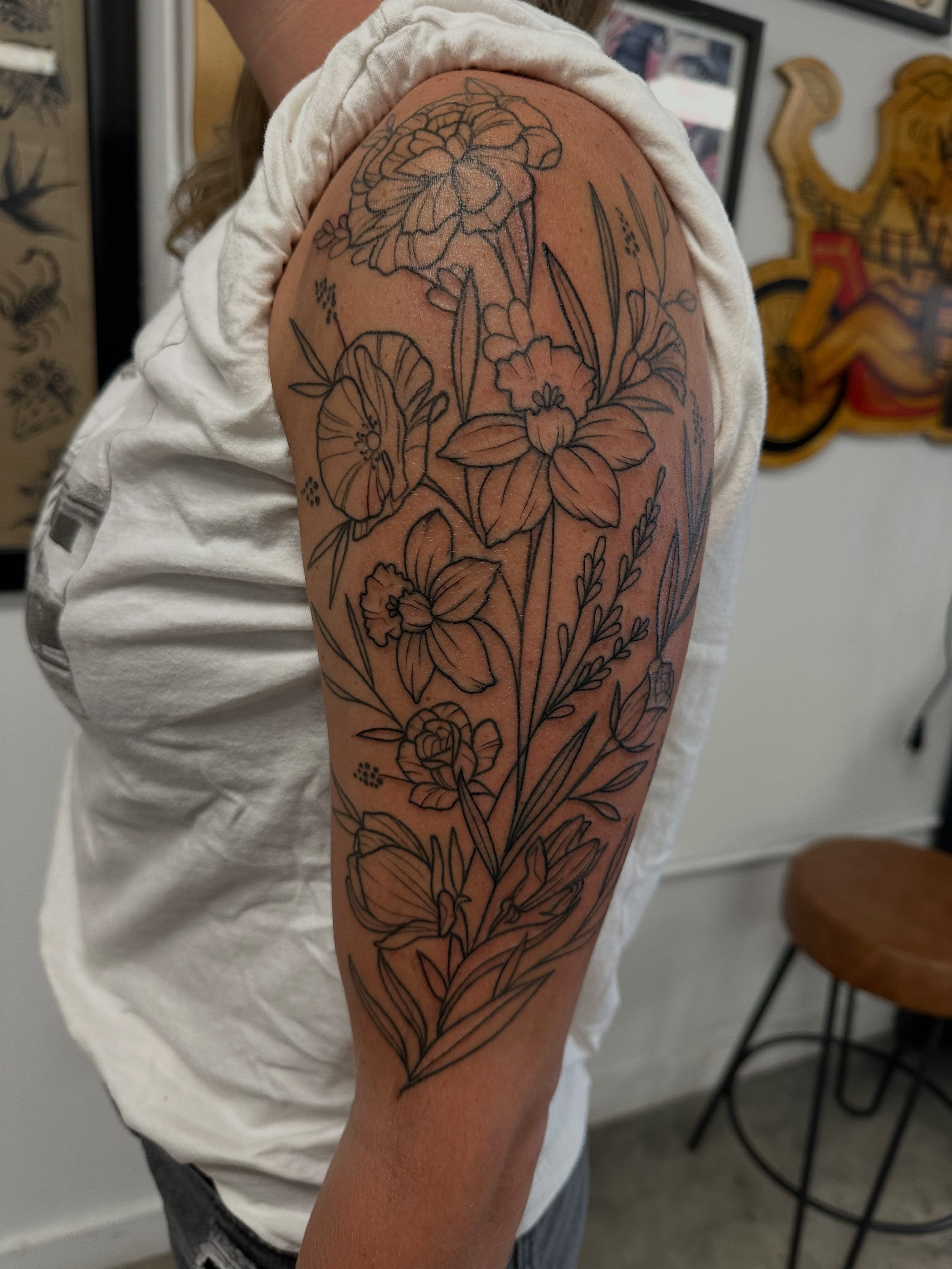 Floral arrangement black and grey tattoo on the upper arm by Vincent Merys