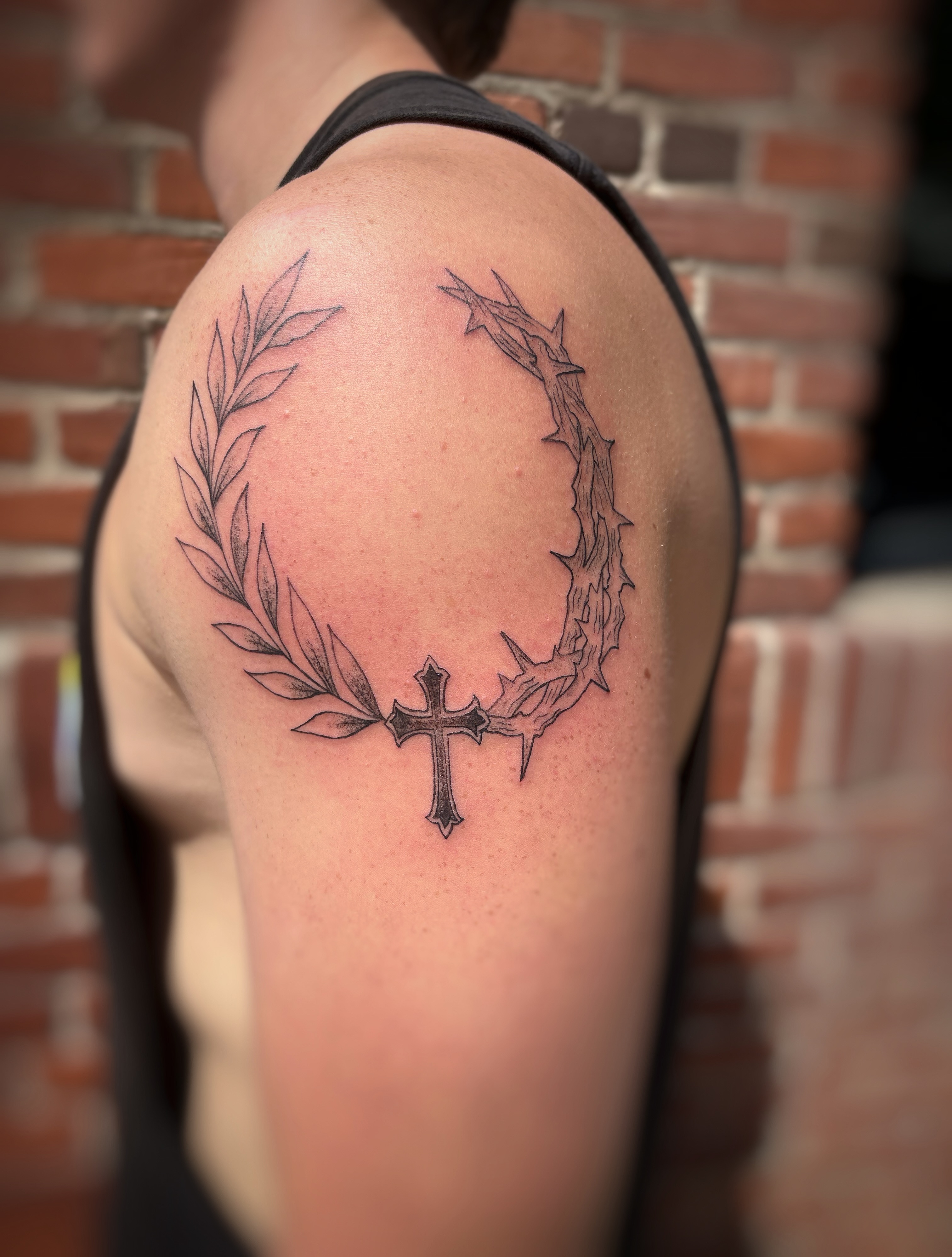 Crown of thorns and cross black and grey tattoo on the shoulder by Holly