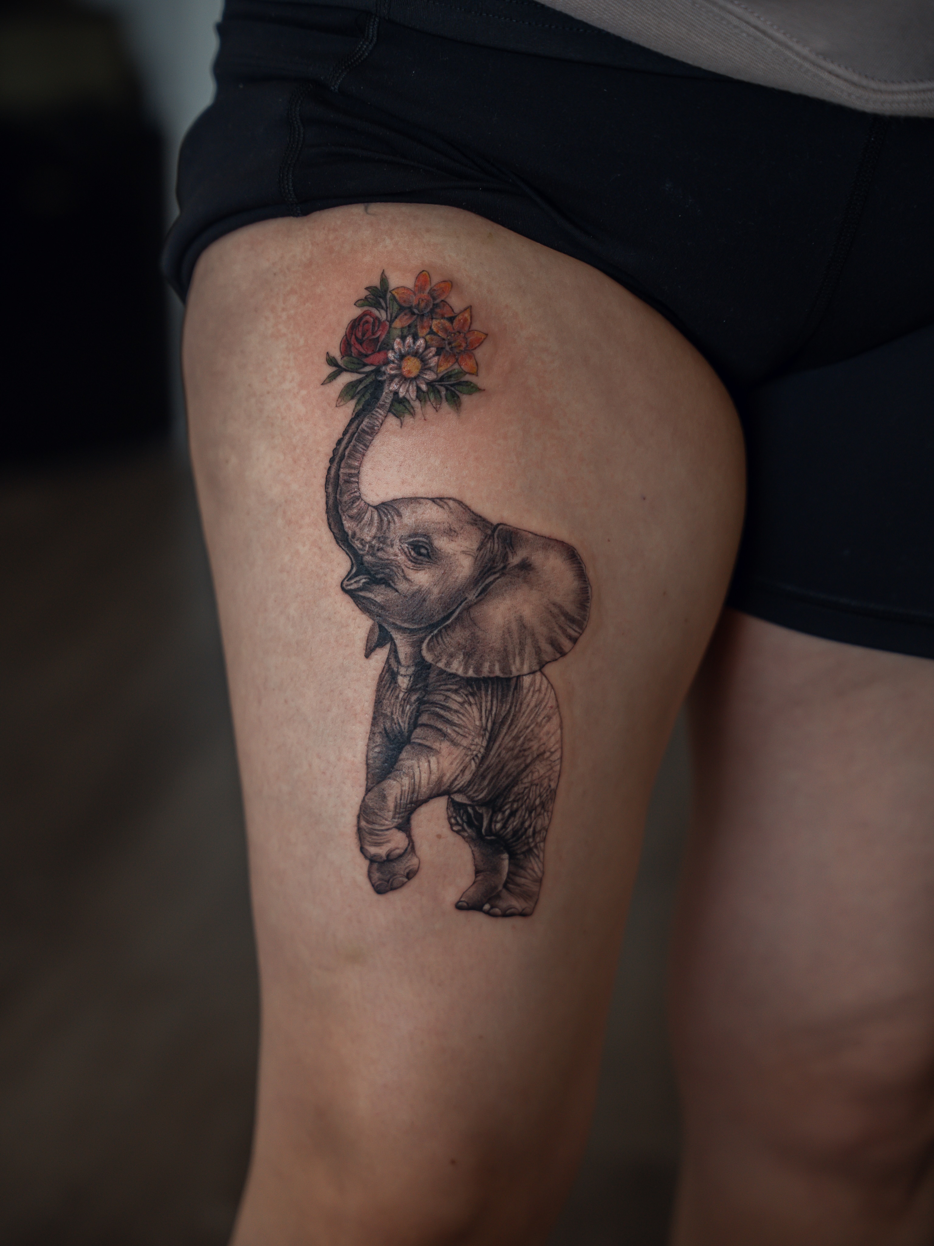 Baby elephant with flowers black and grey tattoo on the thigh by Christopher Espino, Hawthorne, California