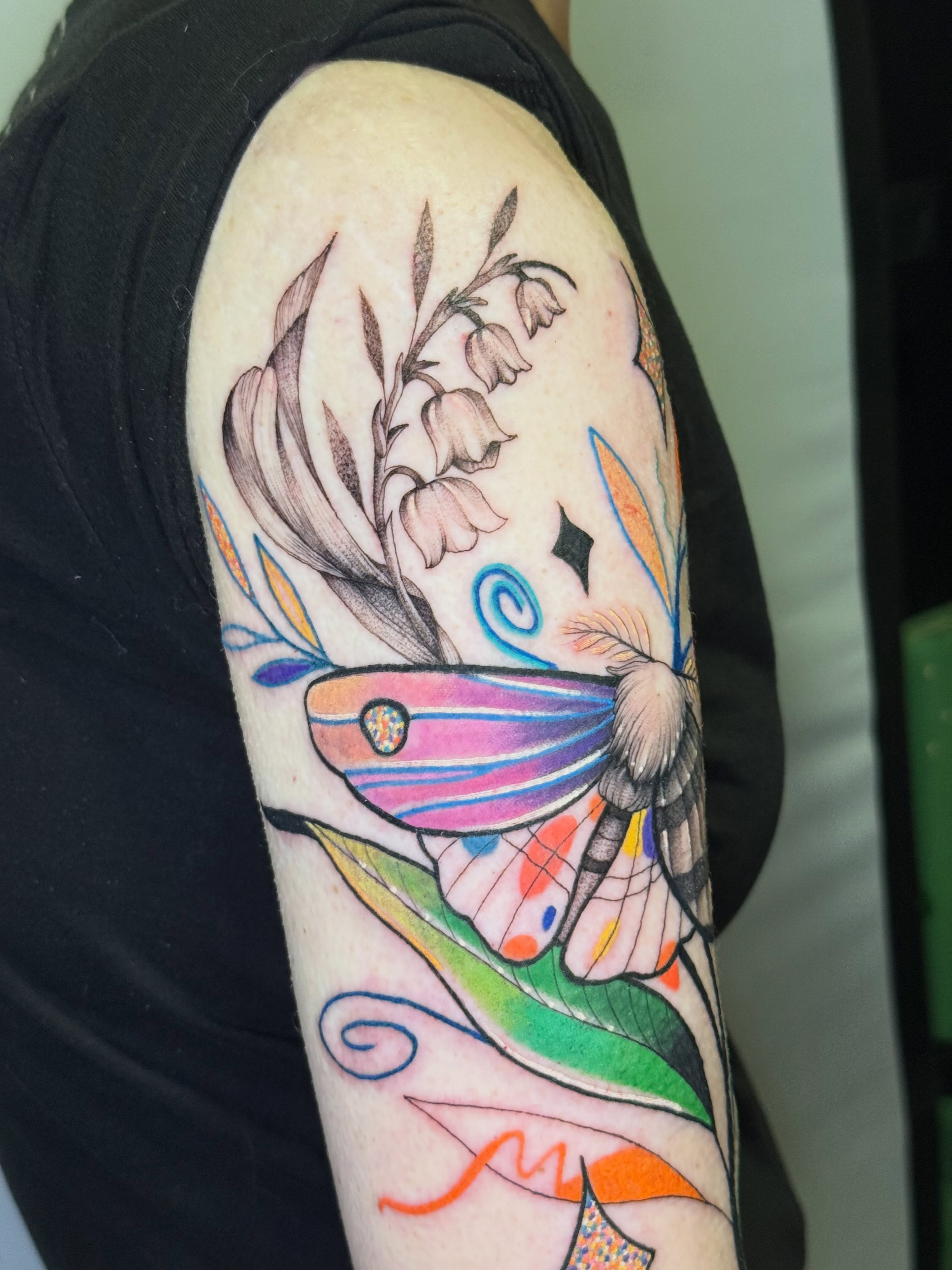 Butterfly and flowers new school tattoo on the upper arm by Diana Muresan