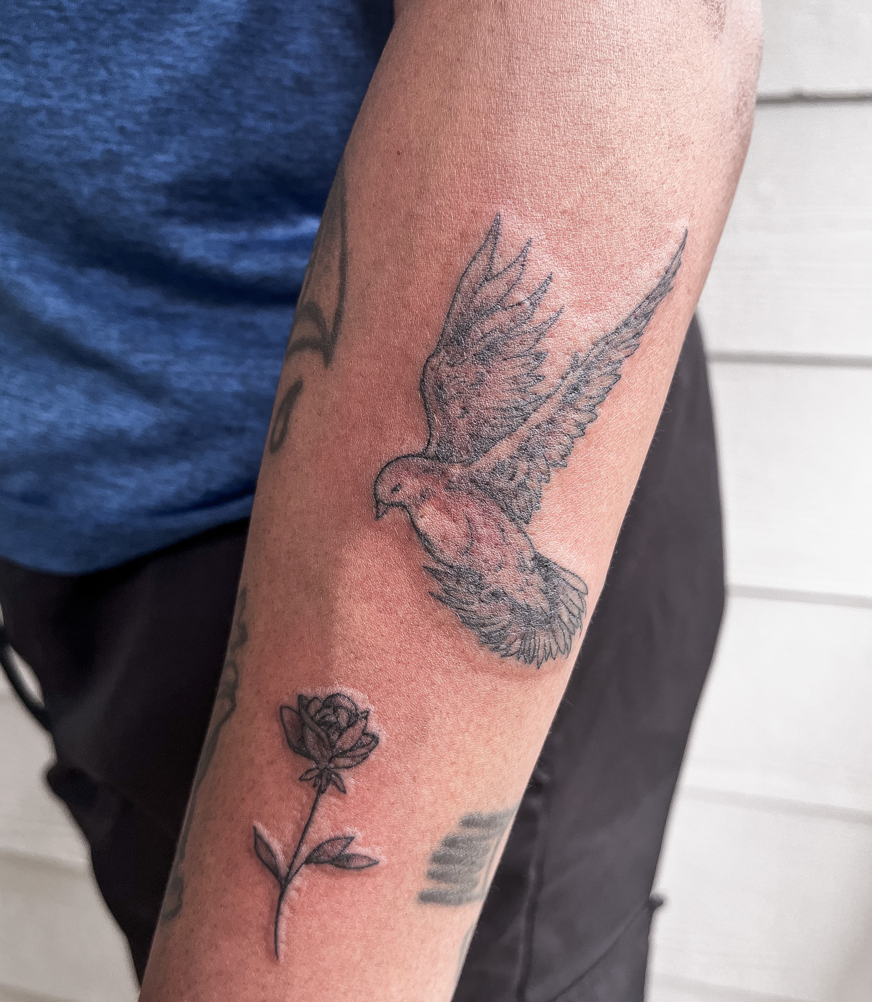 Bird and rose black and grey tattoo on the forearm by Janelle Cuba