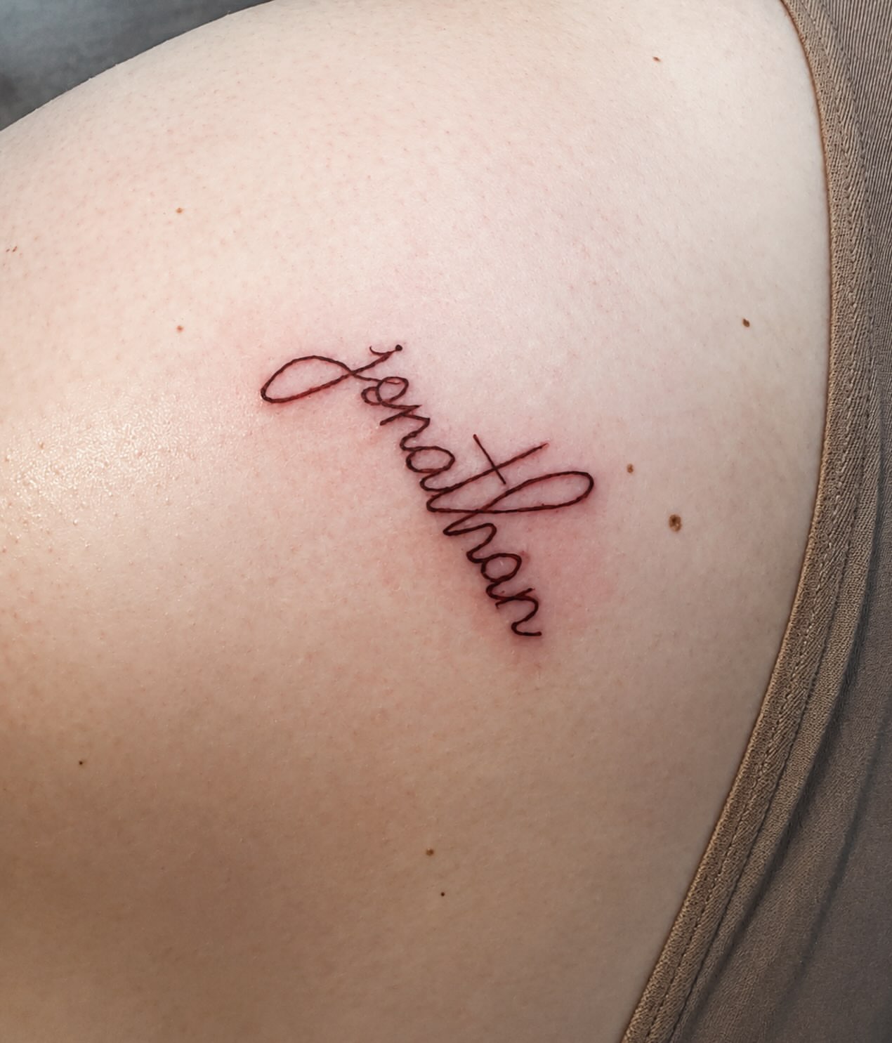Name lettering script tattoo on the shoulder by Victoria Cooper