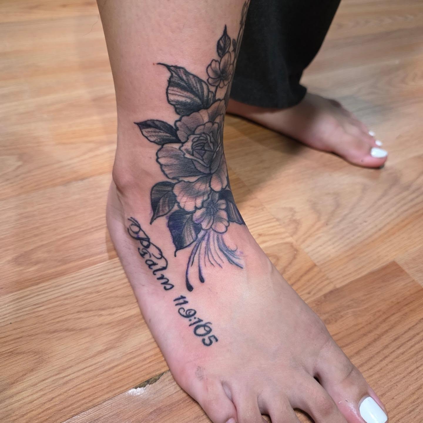 Flowers and scripture black and grey tattoo on the foot by Rusty Williams