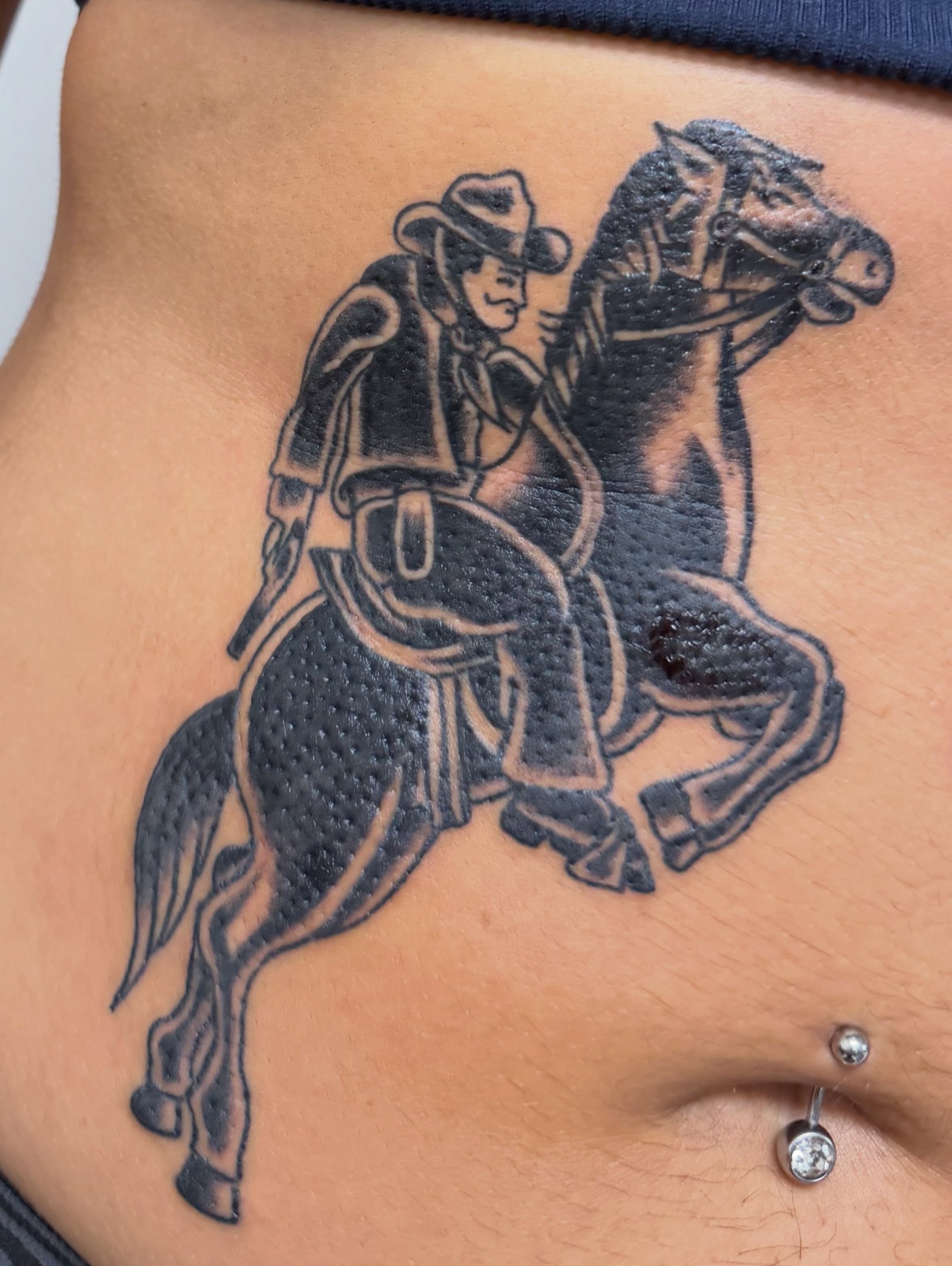Cowboy riding horse black and grey tattoo on the ribs by Bridget Smith