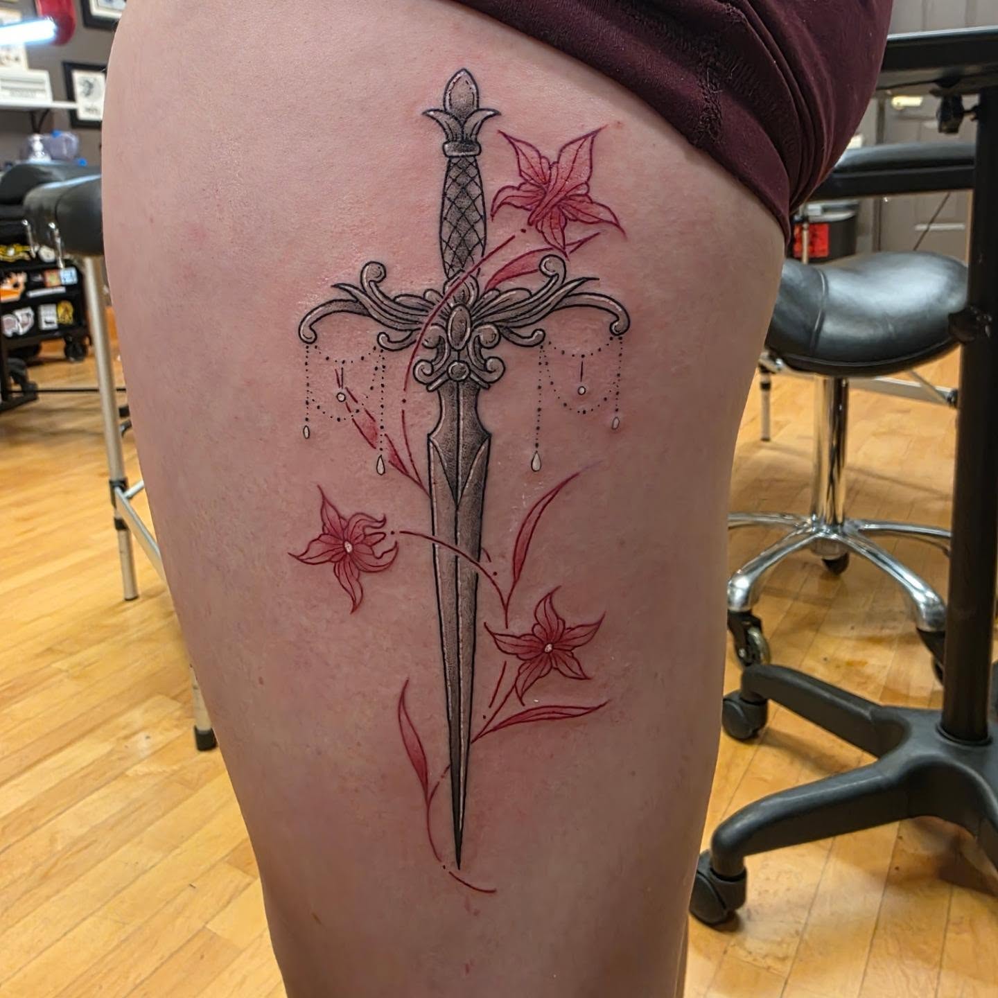 Sword and flowers dotwork tattoo on the thigh by Tattoos by Annie