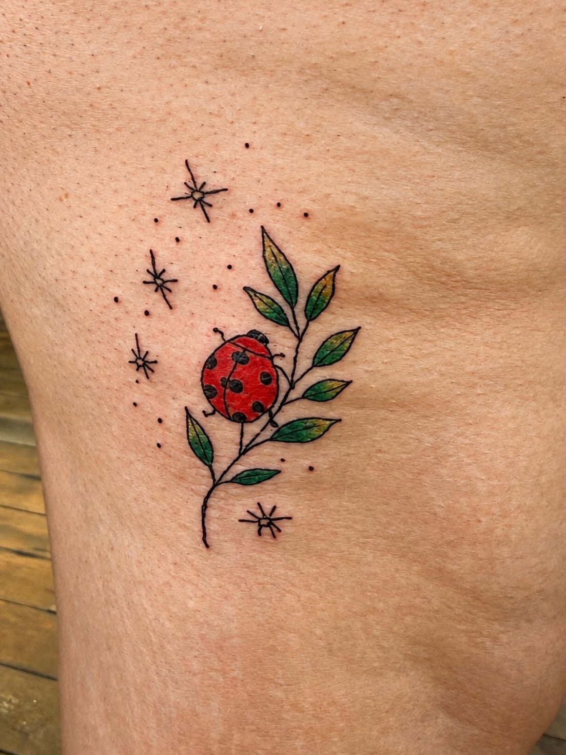 Ladybug and leaf dotwork tattoo on the thigh by Whimsy Ink