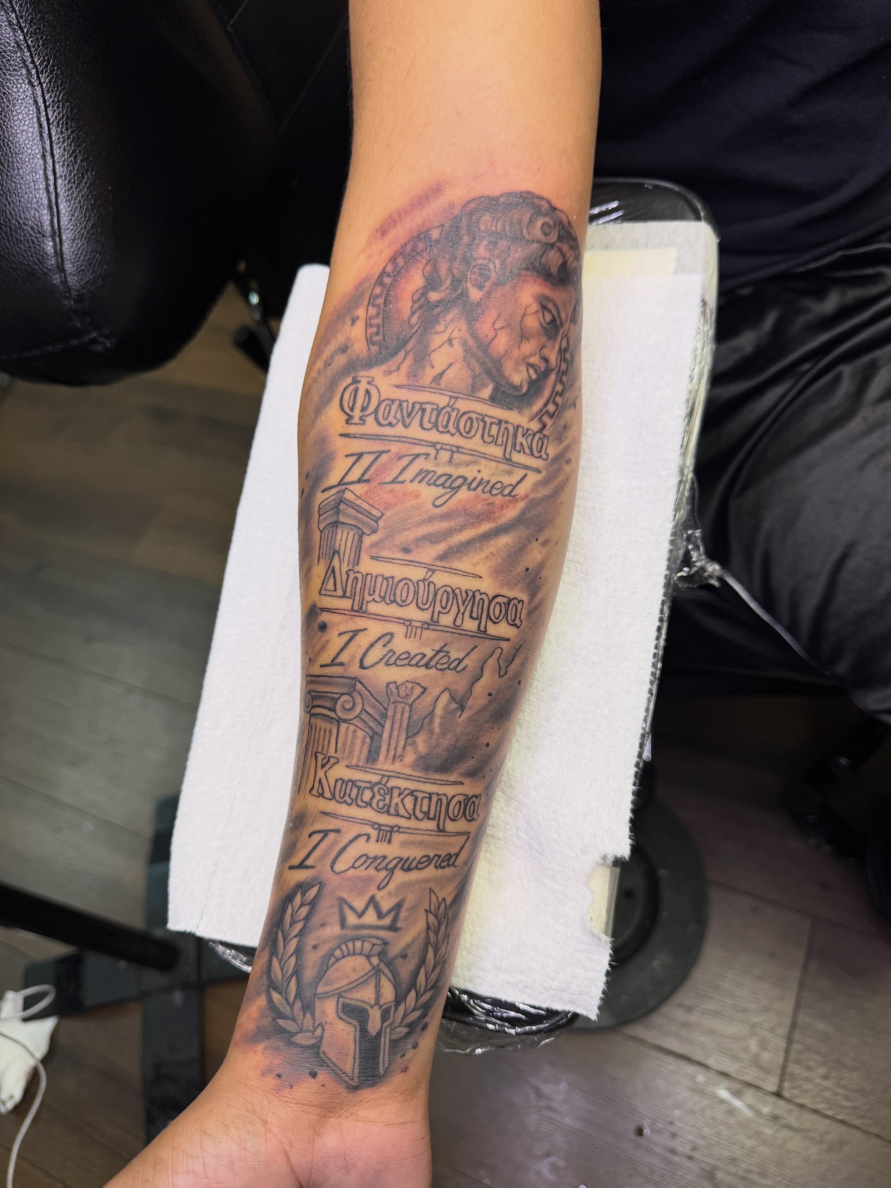 Ancient figure with inscriptions black and grey tattoo on the forearm by Christian Goines, Memphis, Tennessee