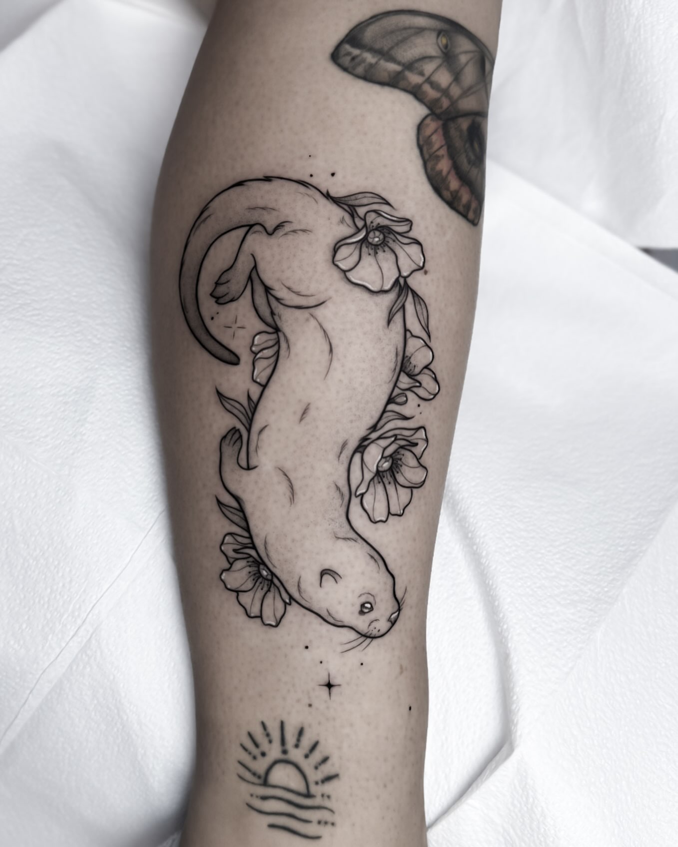 Manatee and flowers realism tattoo on the forearm by Whimsical Tattoos