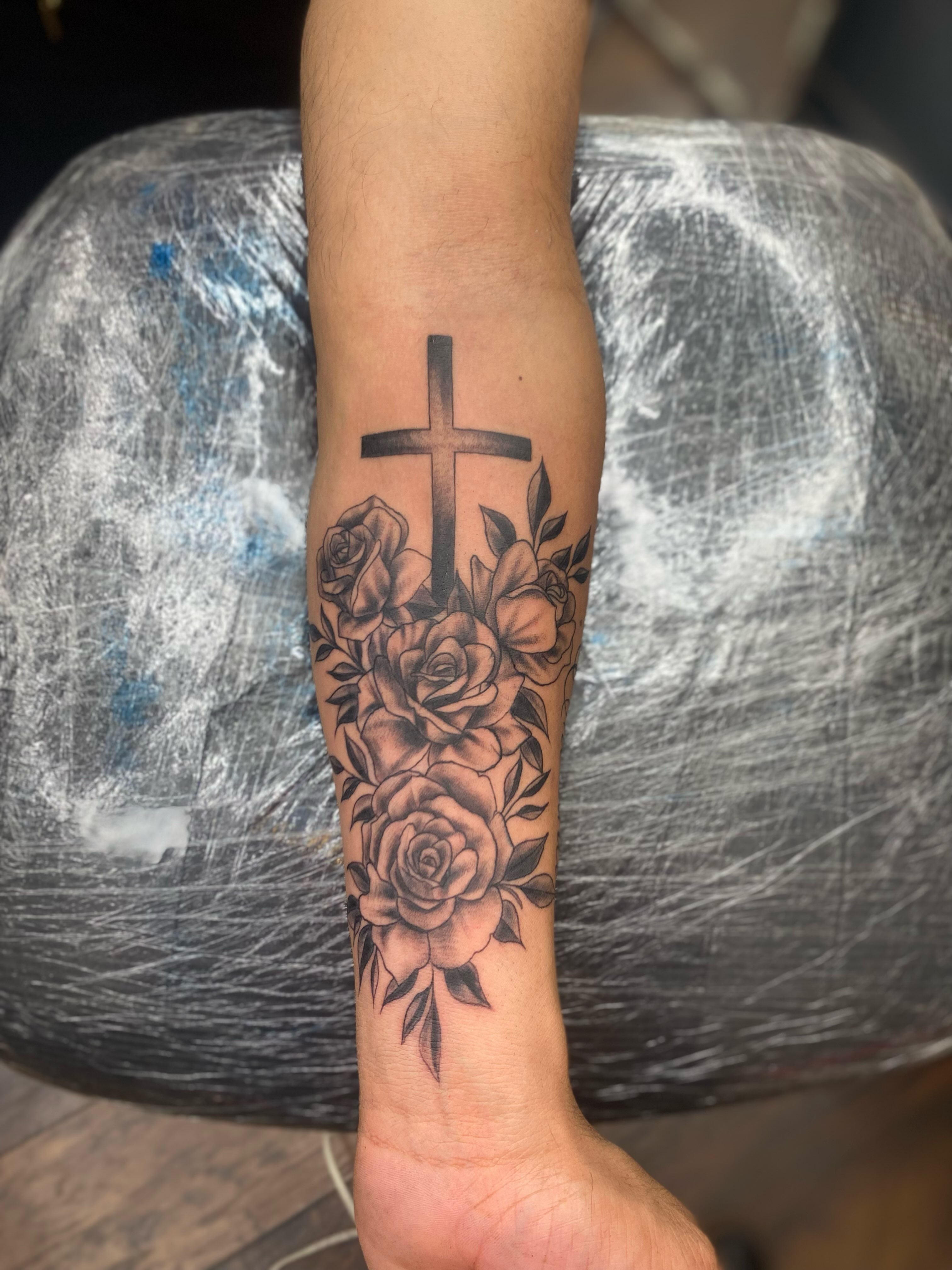 Cross and roses black and grey tattoo on the forearm by Irving Guzman