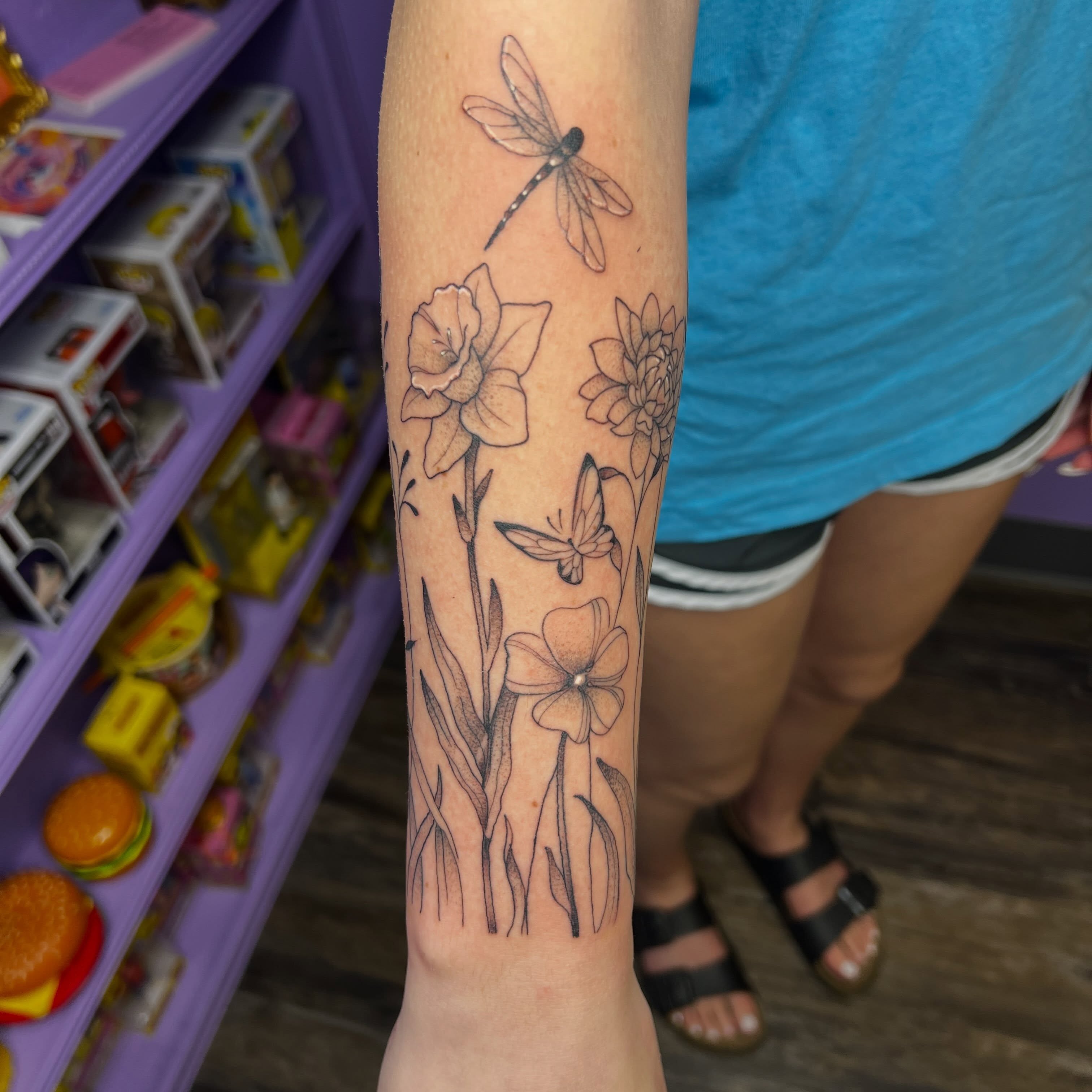 Flowers and dragonfly black and grey tattoo on the forearm by Ebony Robinson, Austintown, Ohio