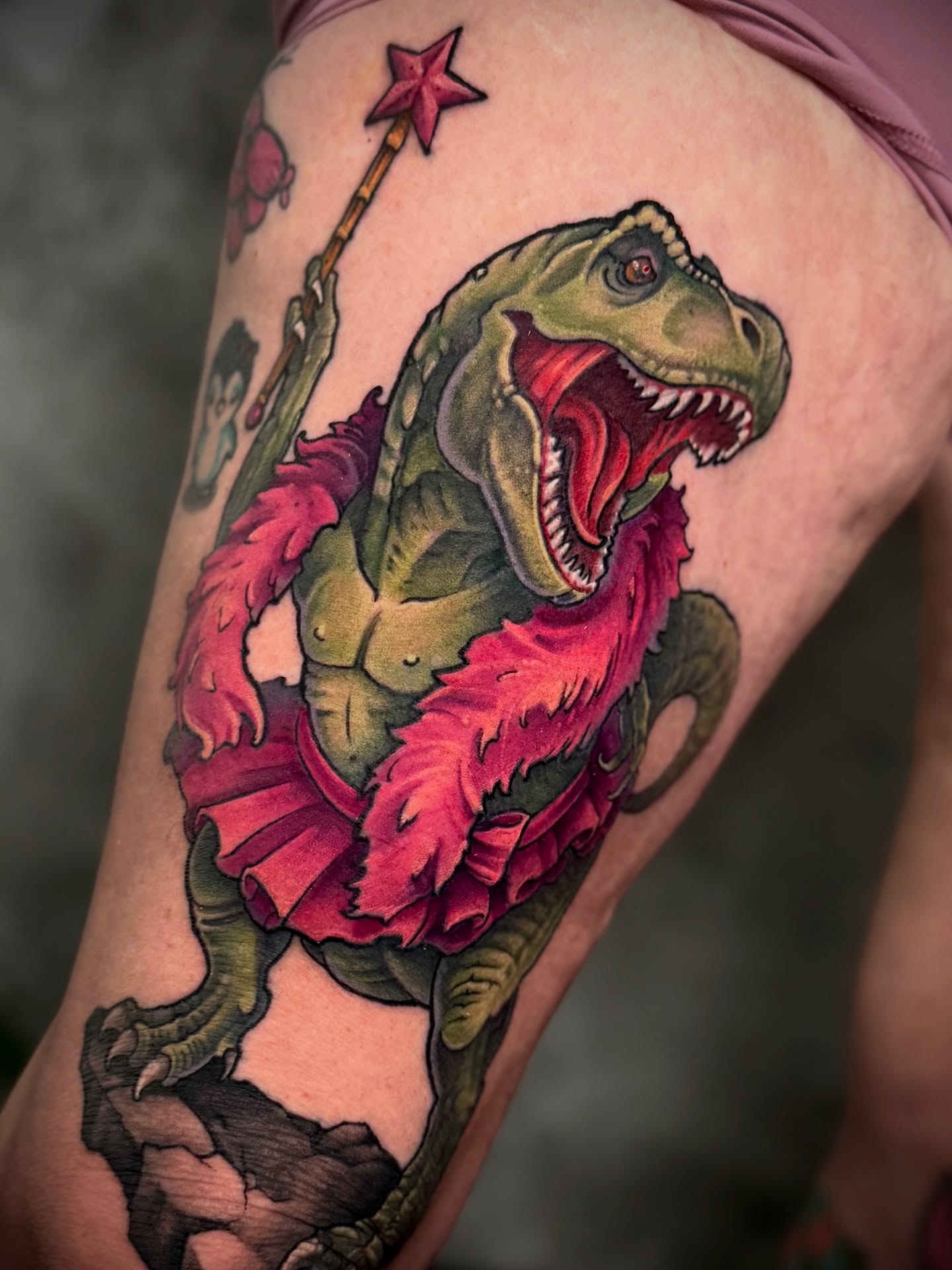 T-Rex with flower realism tattoo on the upper arm by James Hall