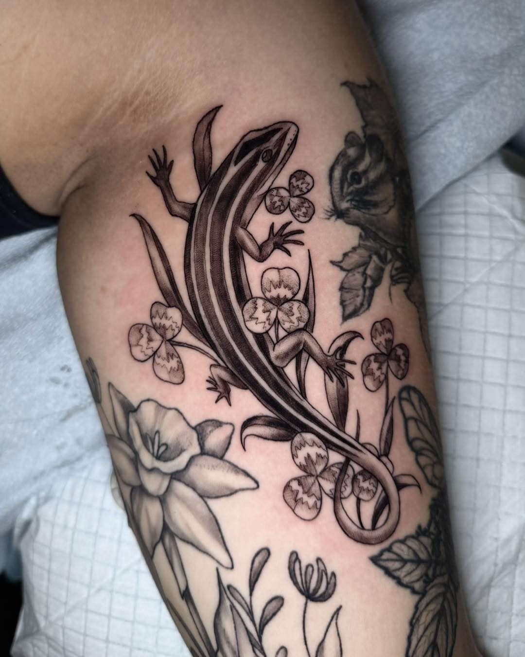 Lizard and flowers black and grey tattoo on the upper arm by Mikaela Rush, Greensboro, North Carolina