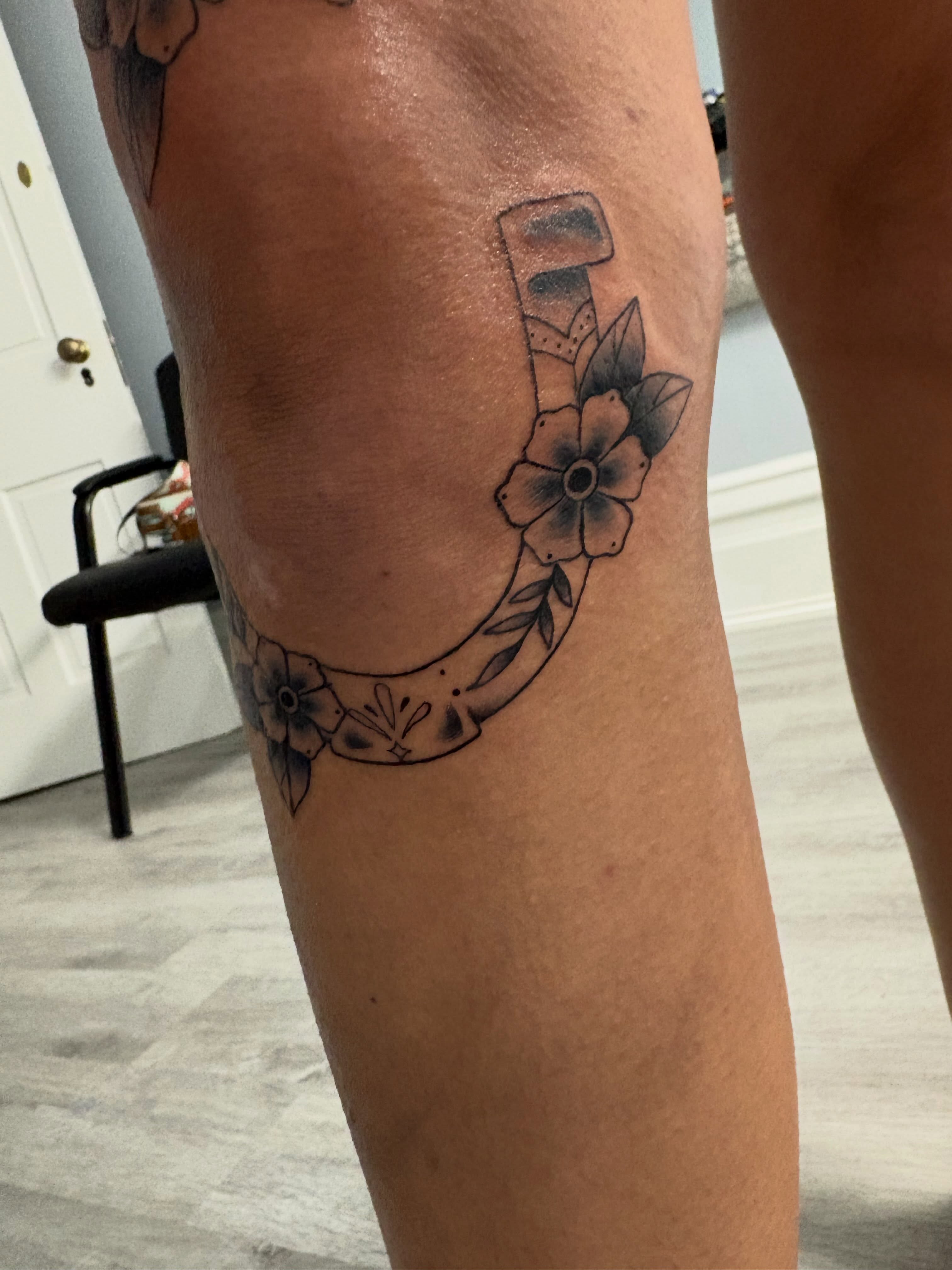 Horseshoe with flowers black and grey tattoo on the leg by Andrea 🎨🖌