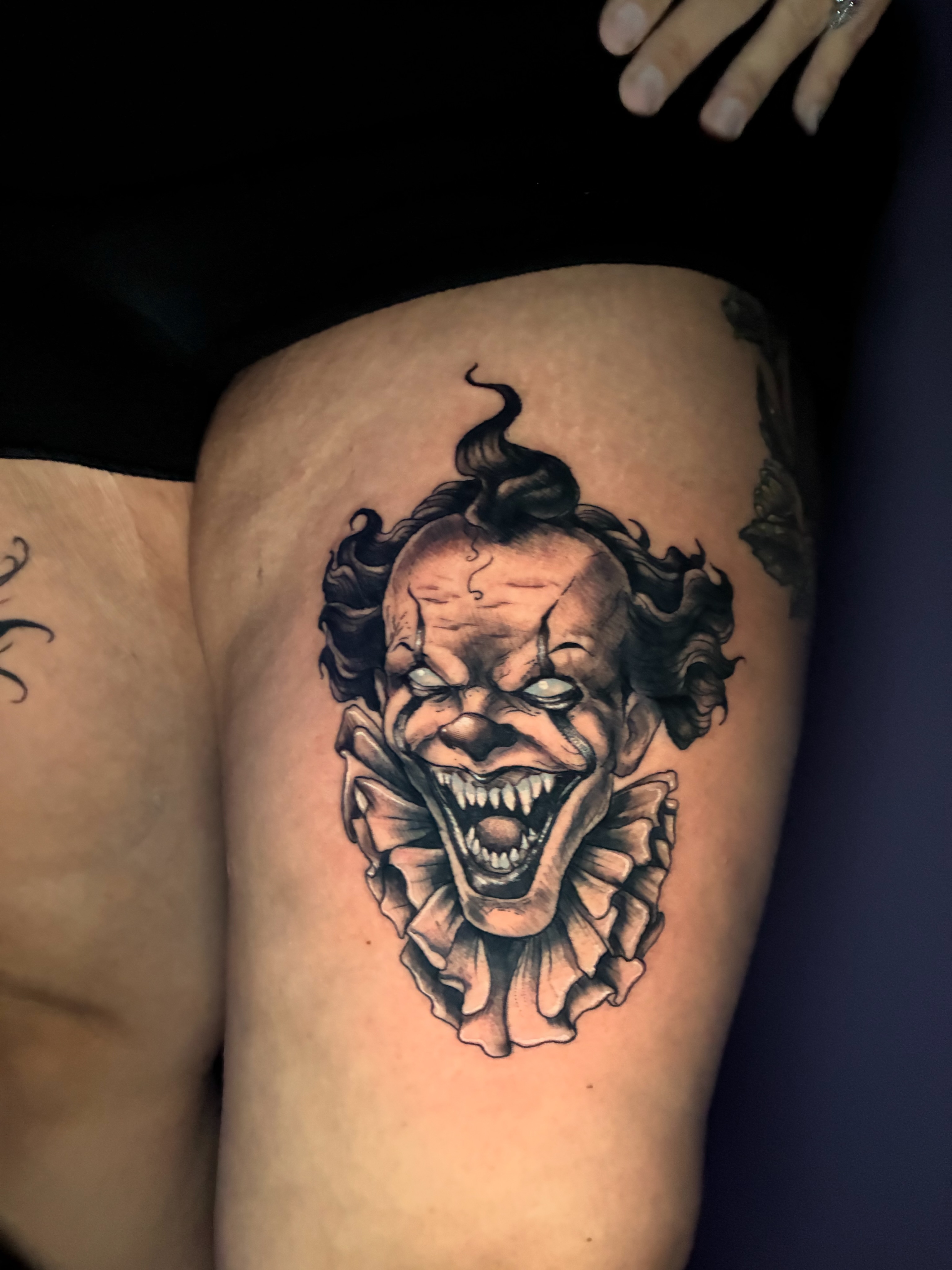Clown black and grey tattoo on the thigh by Frank Miller