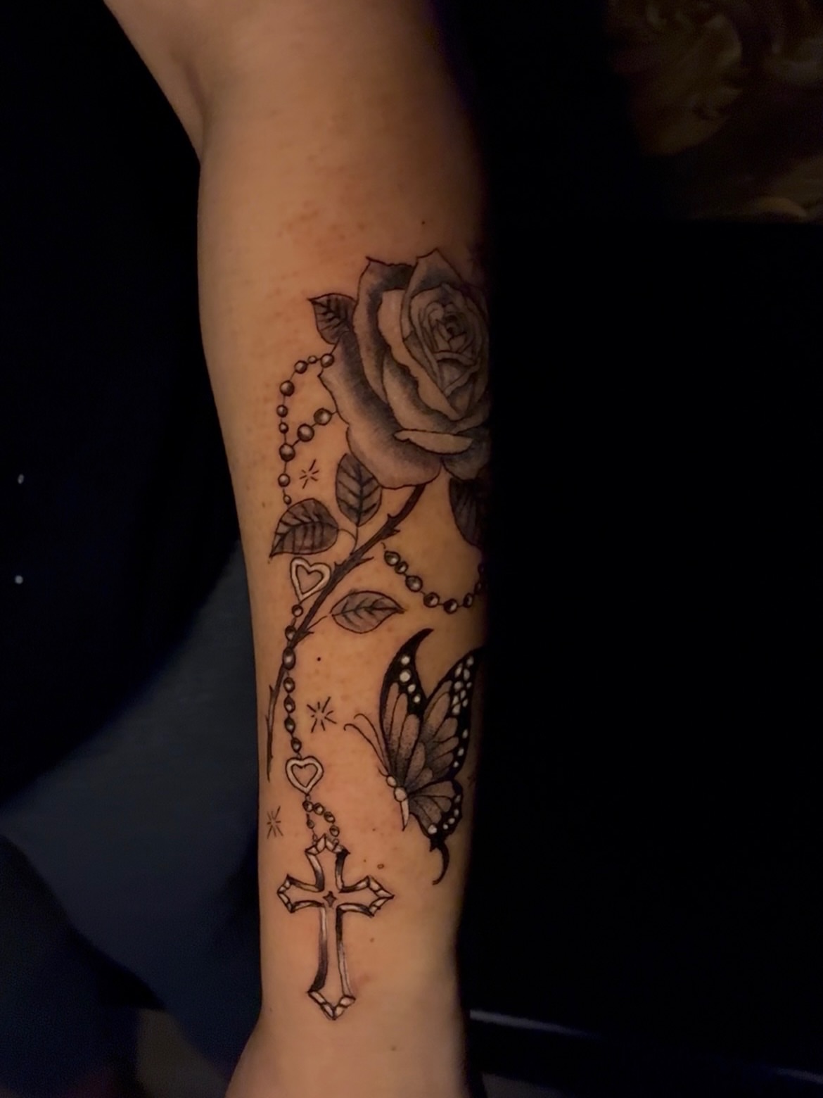 Roses, cross, butterfly black and grey tattoo on the forearm by Tattzbyluma, Charlotte, North Carolina